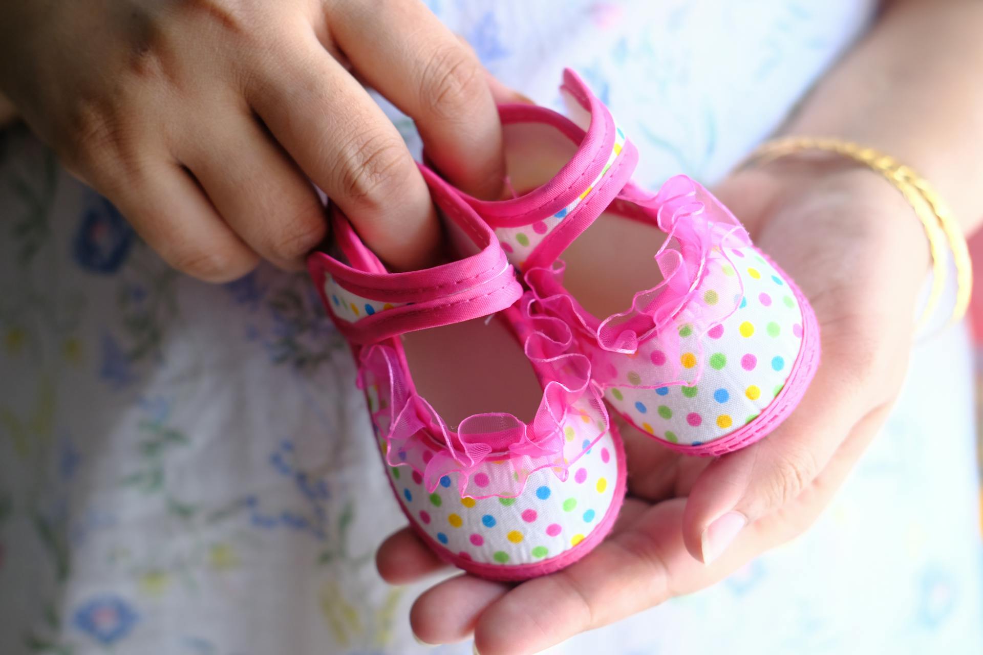 Une femme tenant de minuscules chaussures roses pour bébé | Source : Pexels