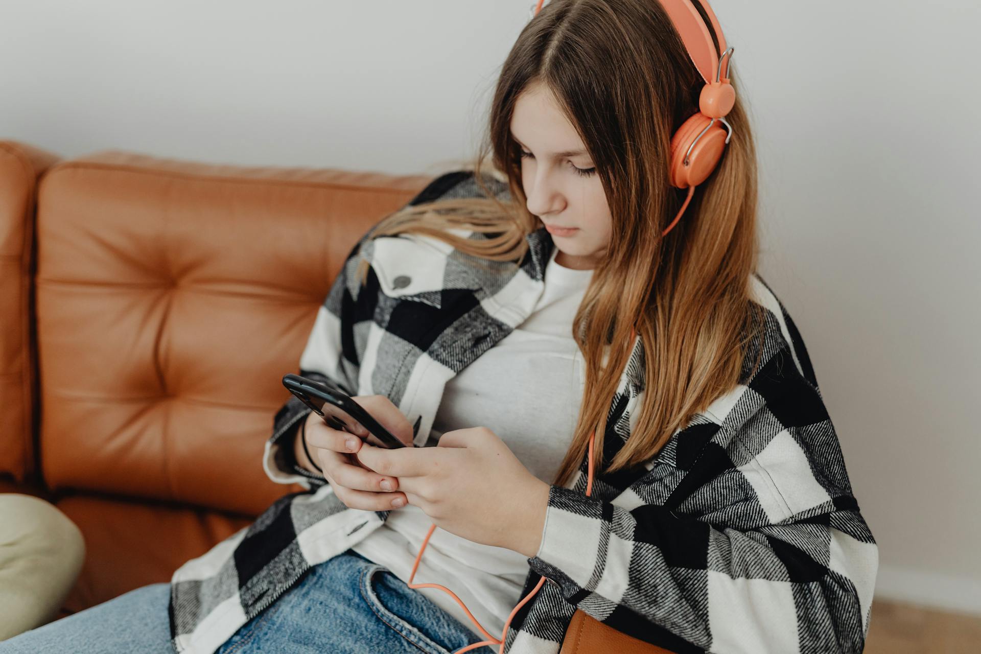 Une jeune fille portant des écouteurs et utilisant son téléphone | Source : Pexels