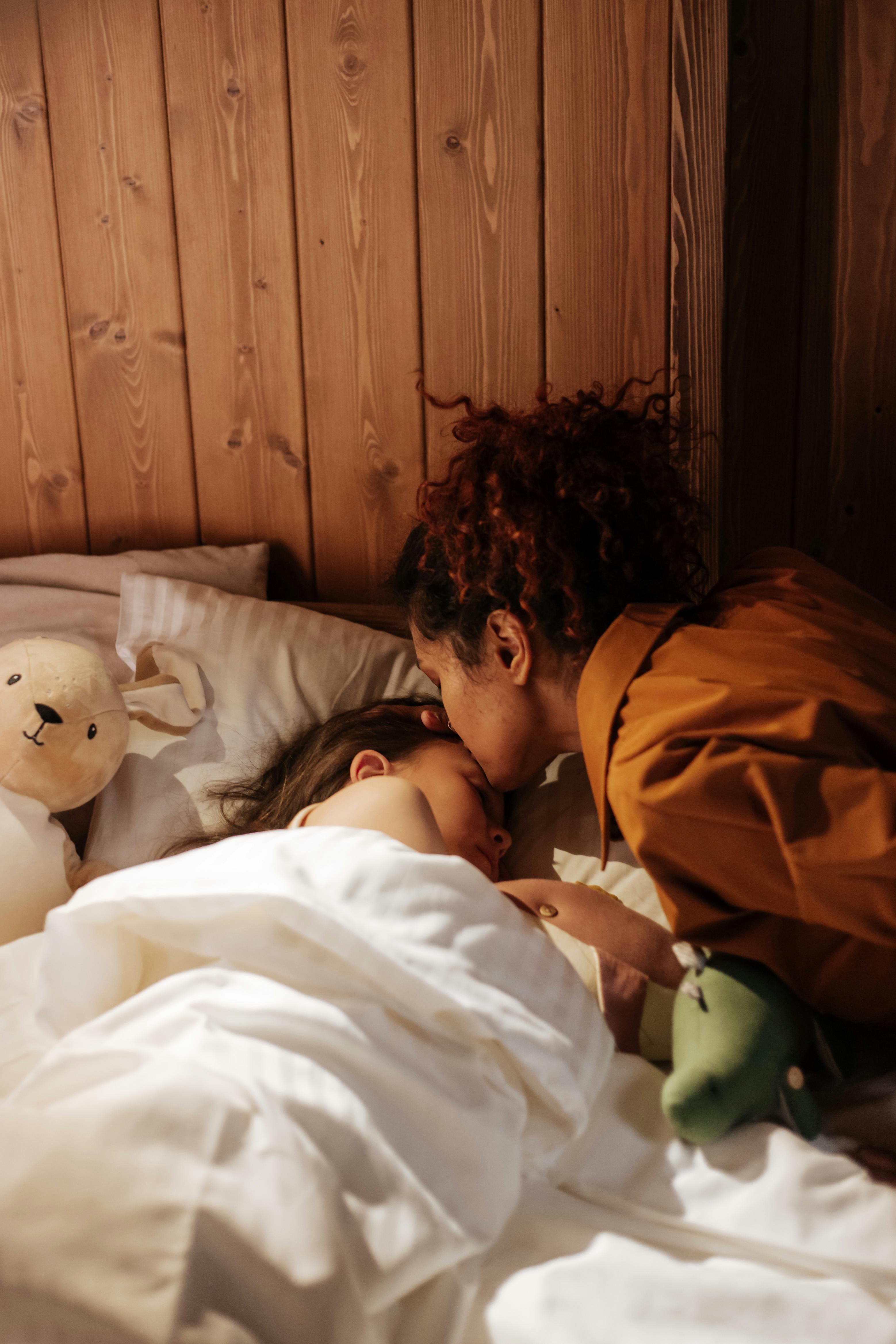 Une mère bordant sa fille dans son lit | Source : Pexels