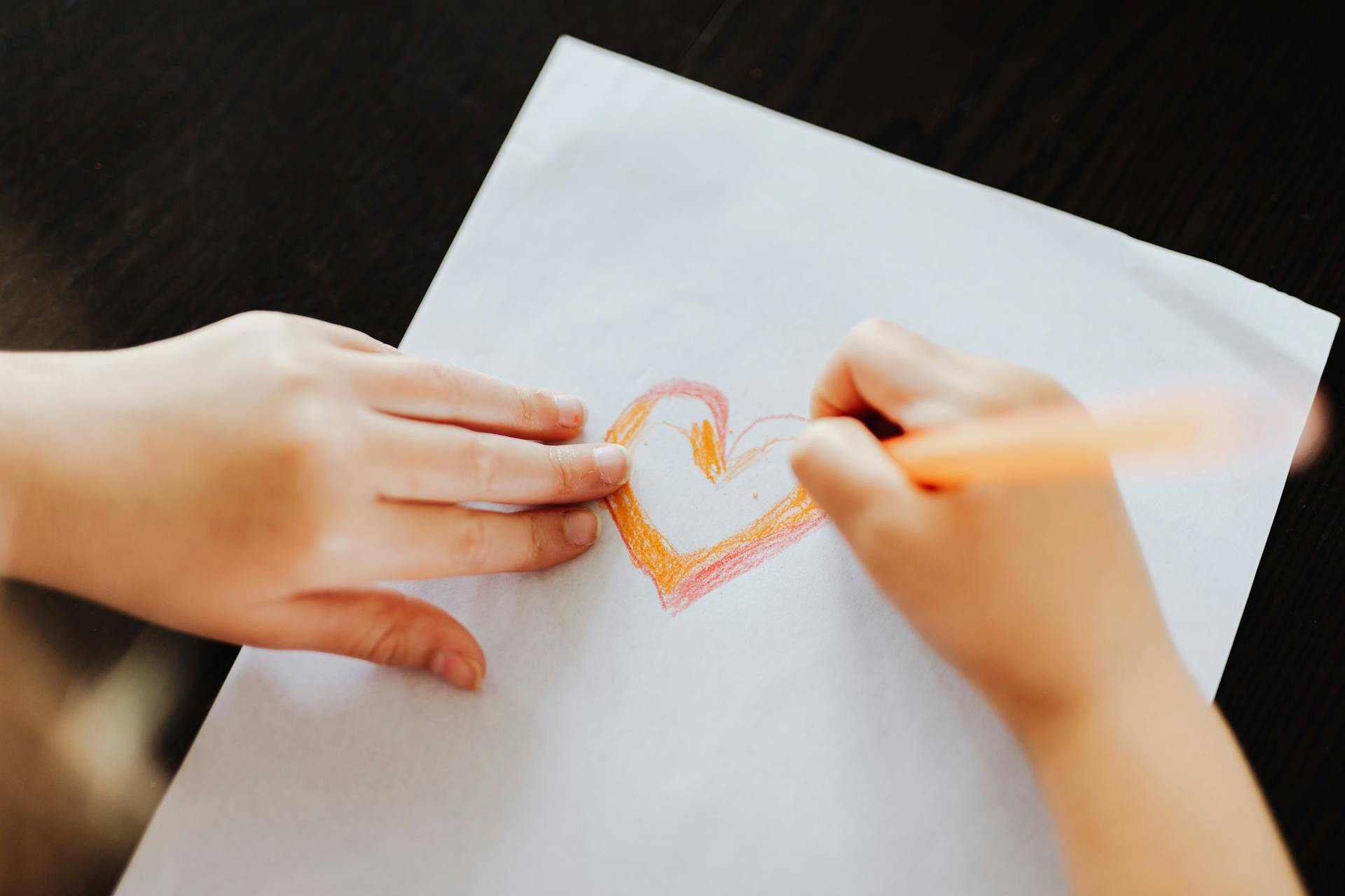Un enfant dessine un cœur sur un morceau de papier | Source : Pexels