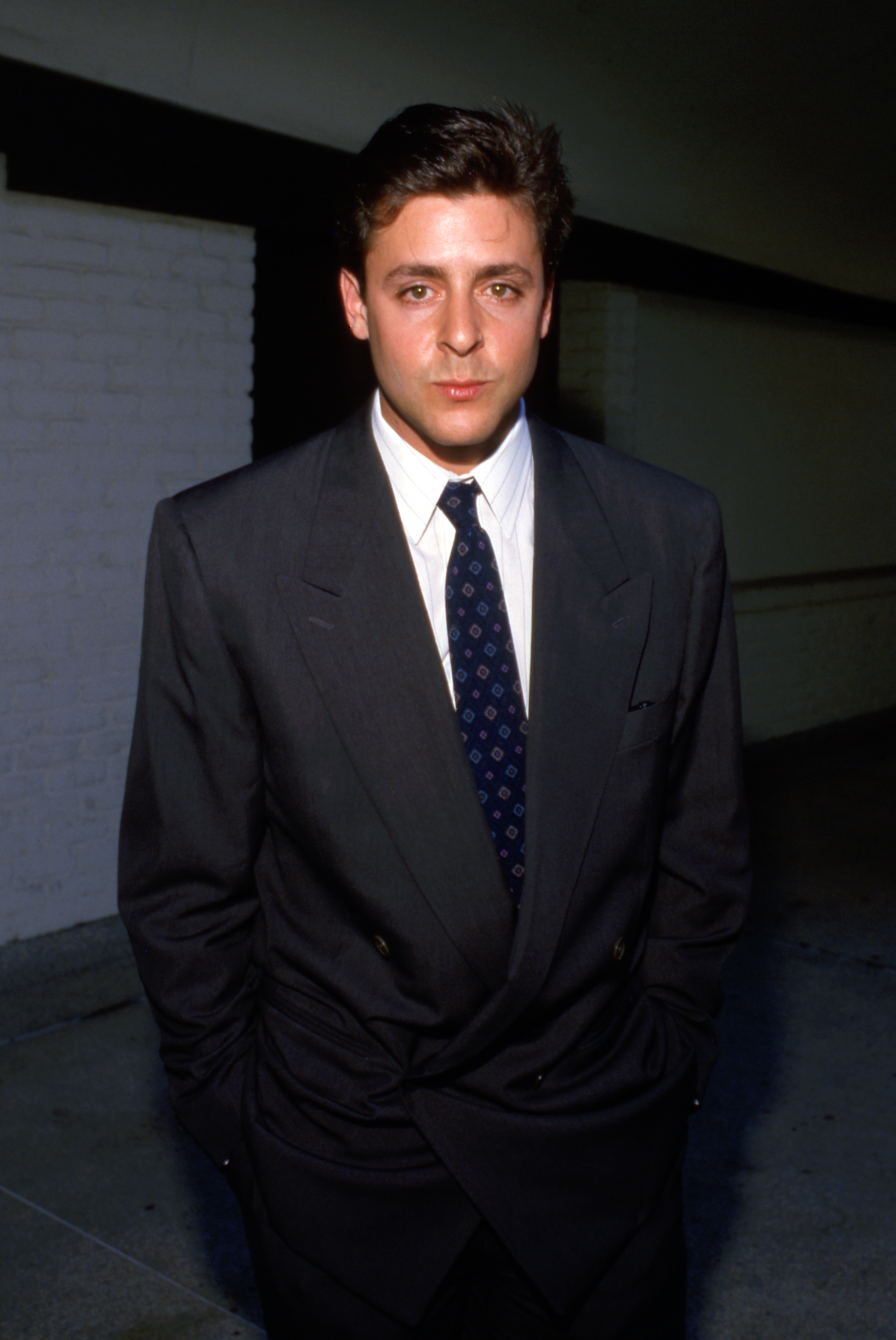 Vêtu d'un élégant costume sombre à double boutonnage et d'une cravate à motifs le 24 février 1989, l'acteur affichait un style classique et soigné alors que la fin des années 80 touchait à sa fin. | Source : Getty Images