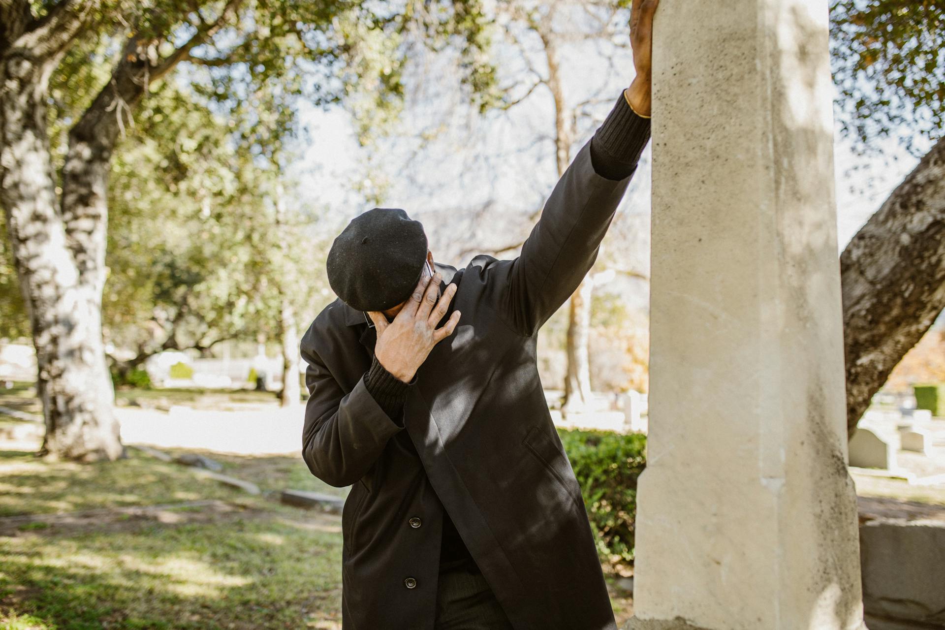 Un homme en deuil se tenant à côté d'une structure en béton grise | Source : Pexels
