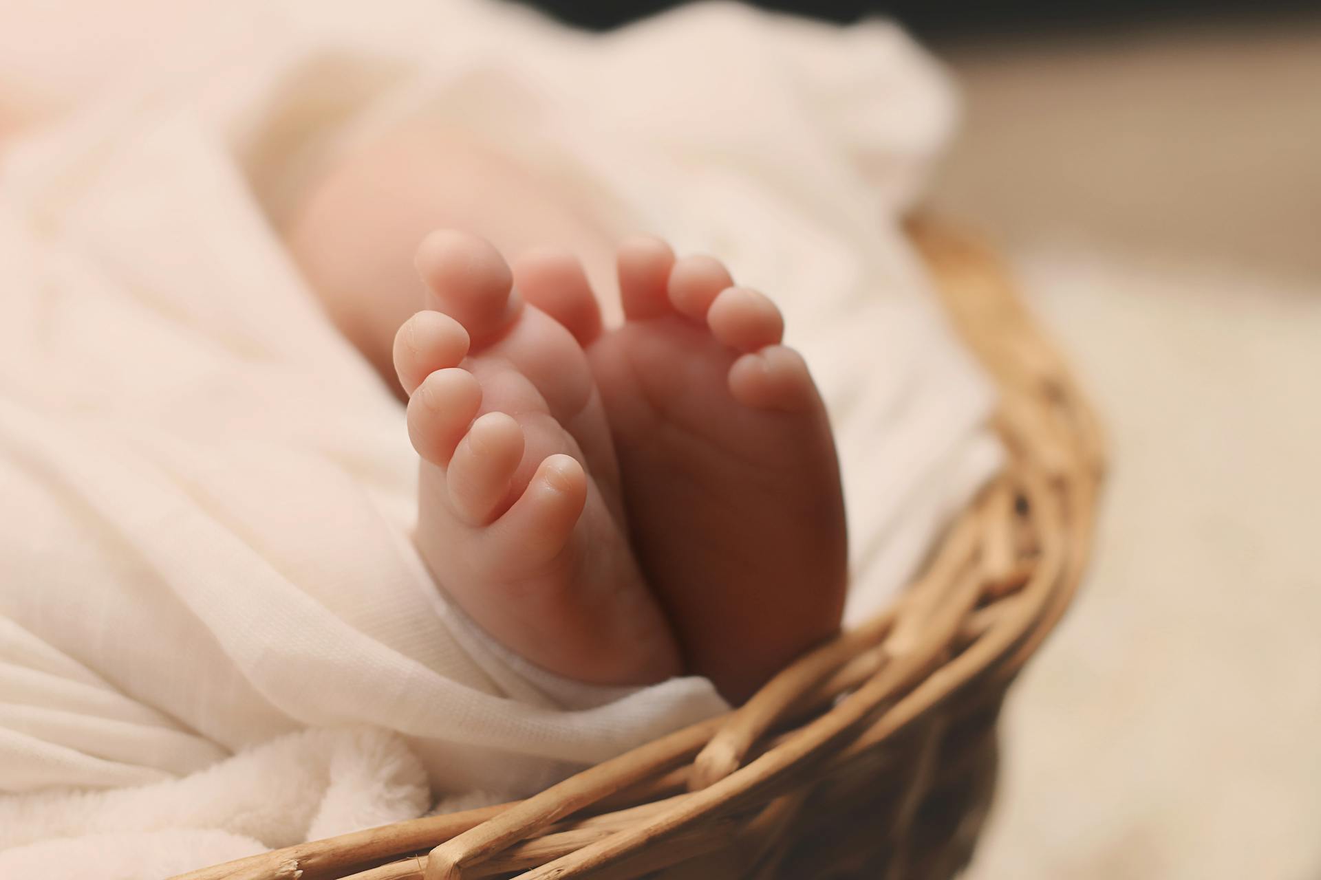 Gros plan sur les pieds d'un bébé sur un panier en osier | Source : Pexels