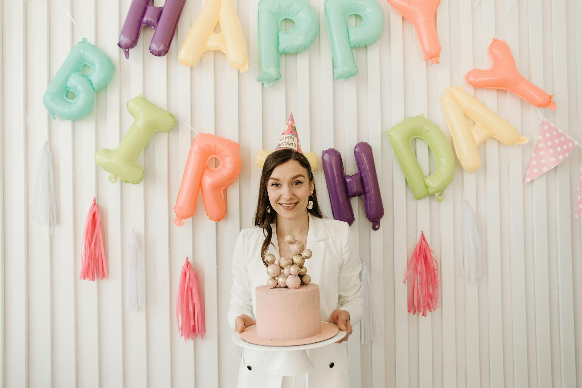 Une femme tenant un gâteau et portant un chapeau de fête | Source : Pexels