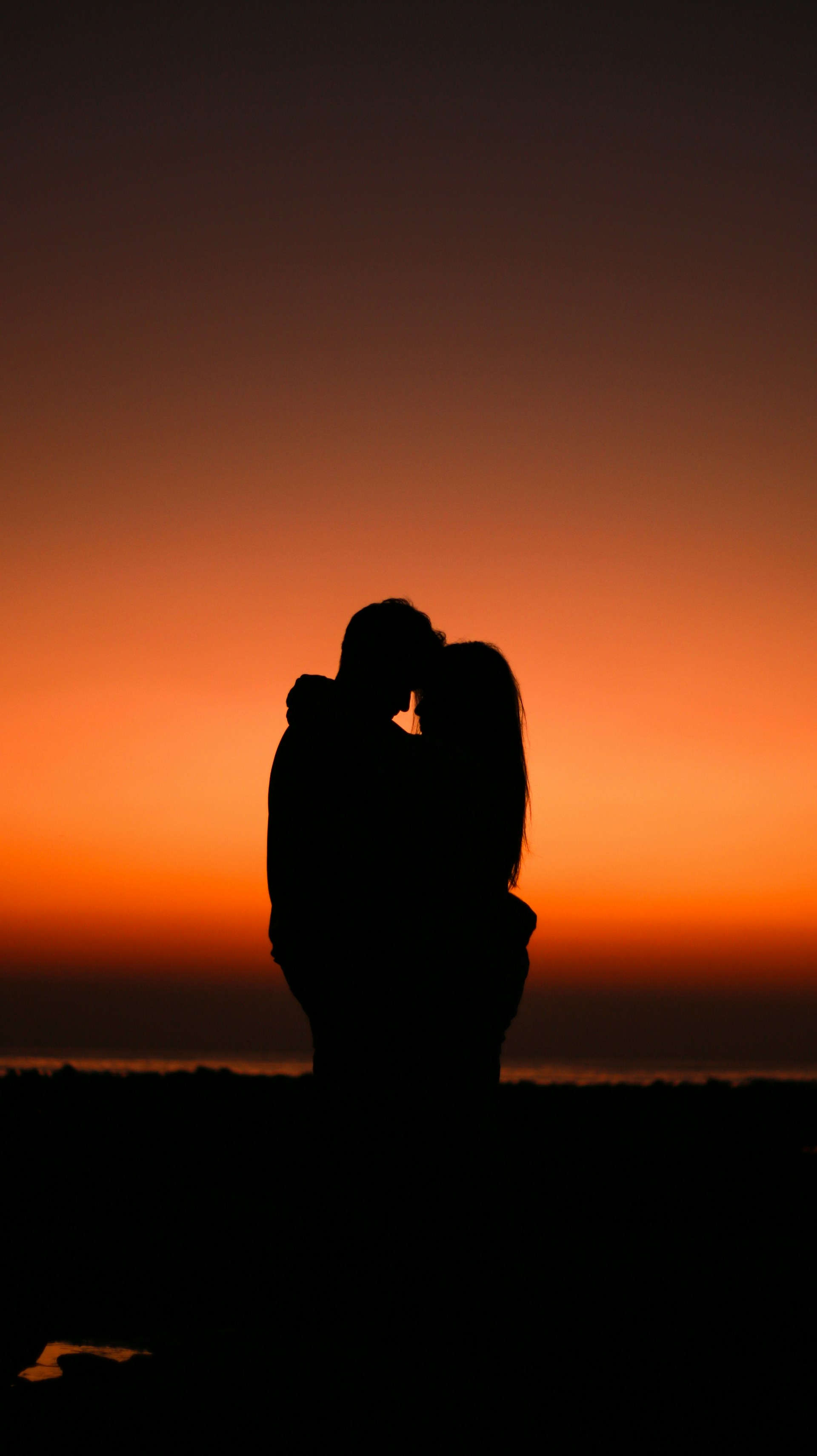 Silhouette d'un couple qui s'enlace par une soirée dorée | Source : Unsplash