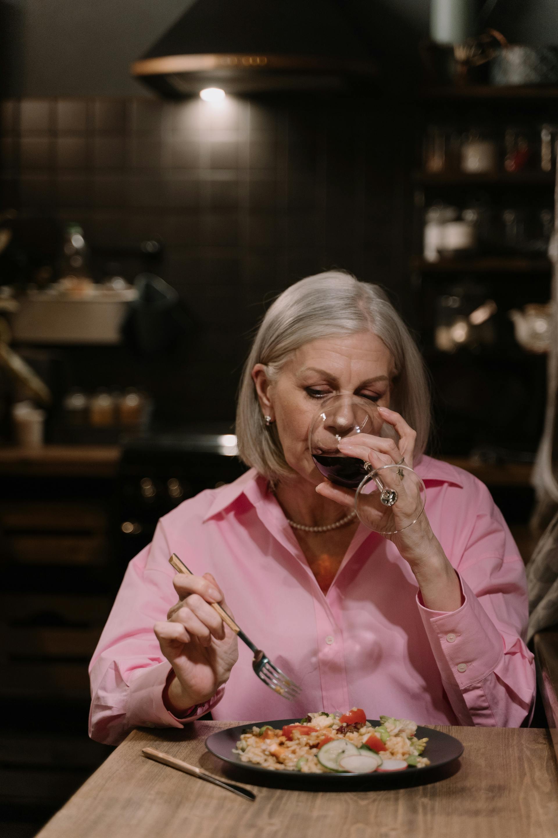 Une femme âgée qui boit du vin en dînant | Source : Pexels