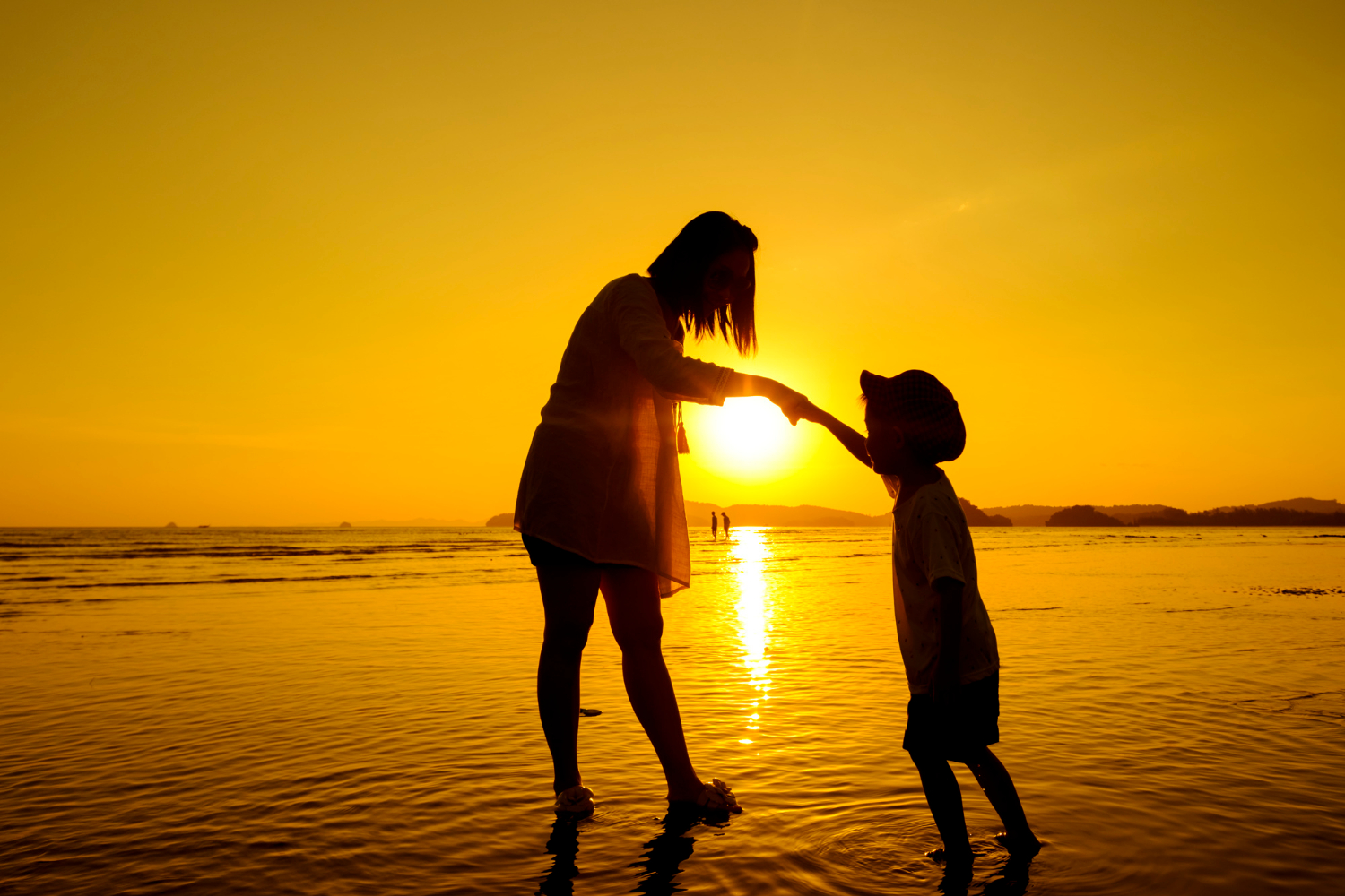 Une mère et son fils sur la plage au coucher du soleil | Source : Freepik