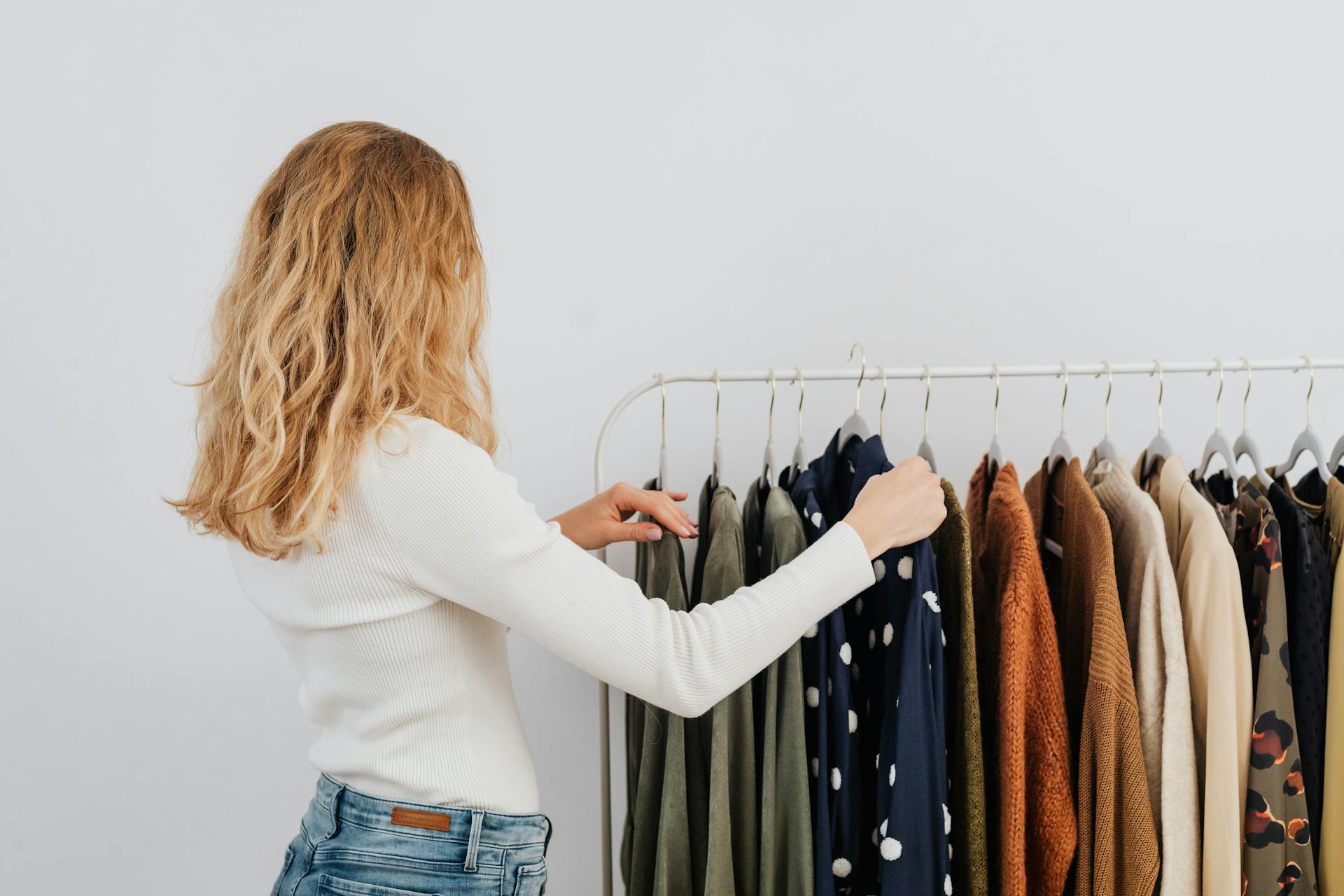 Une femme accroche des vêtements sur une étagère | Source : Pexels