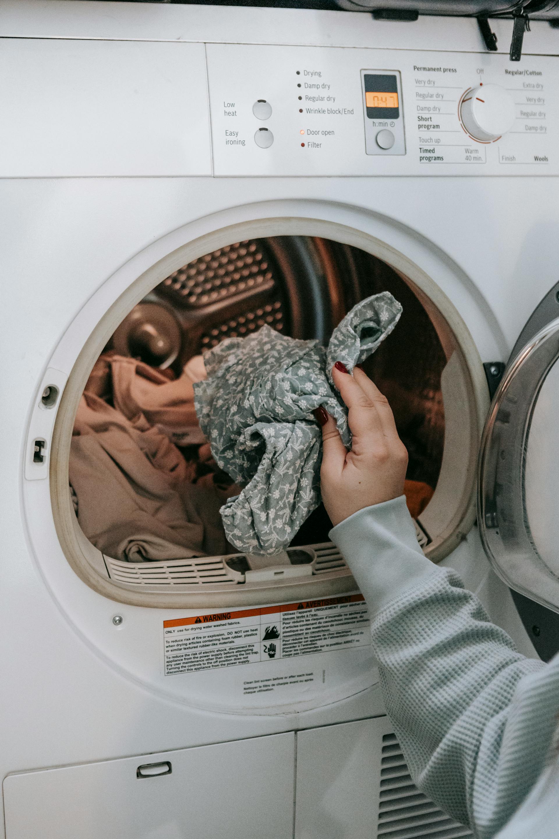 Une femme mettant des vêtements dans une machine à laver | Source : Pexels