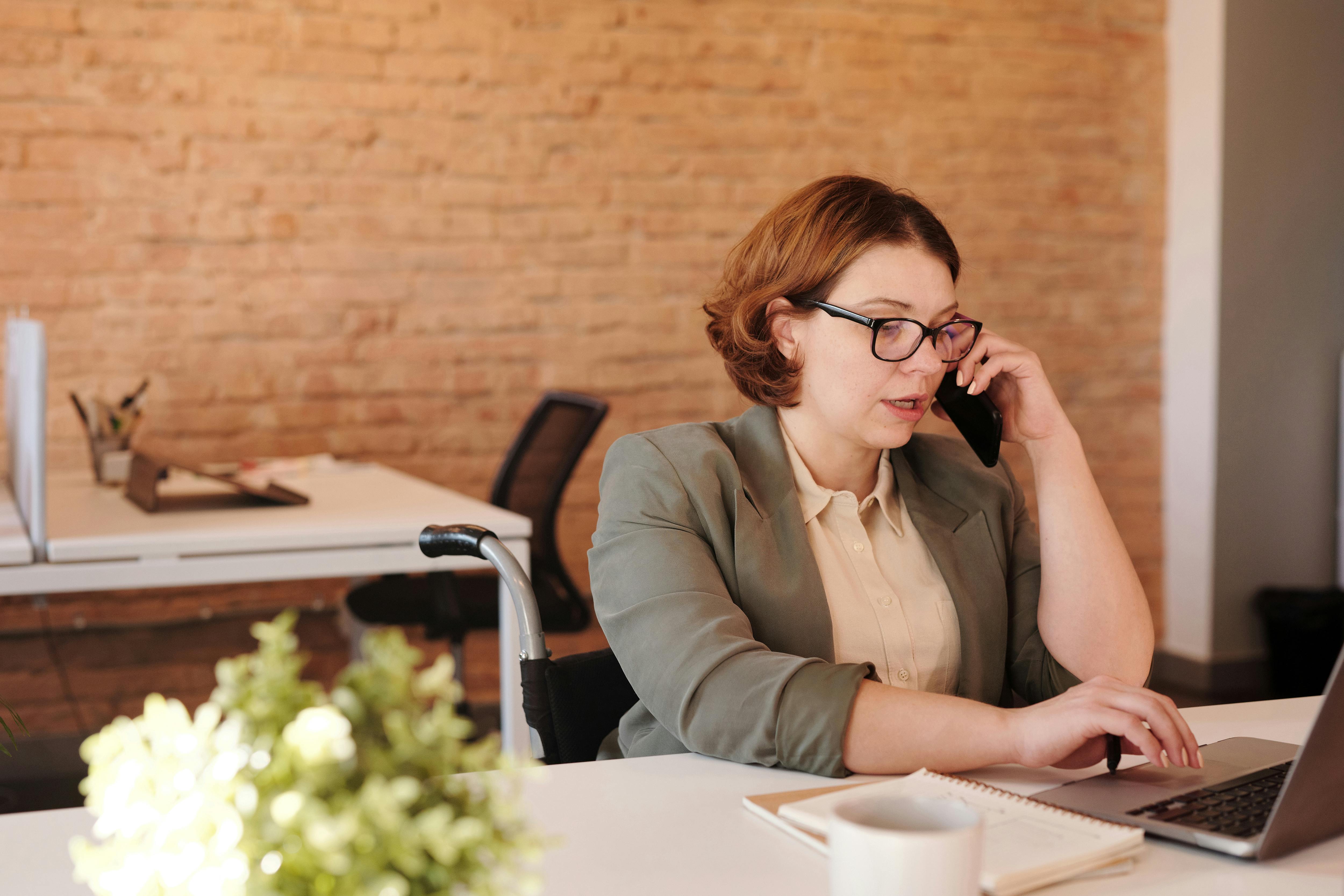 Une femme qui parle au téléphone tout en travaillant sur un ordinateur portable | Source : Pexels