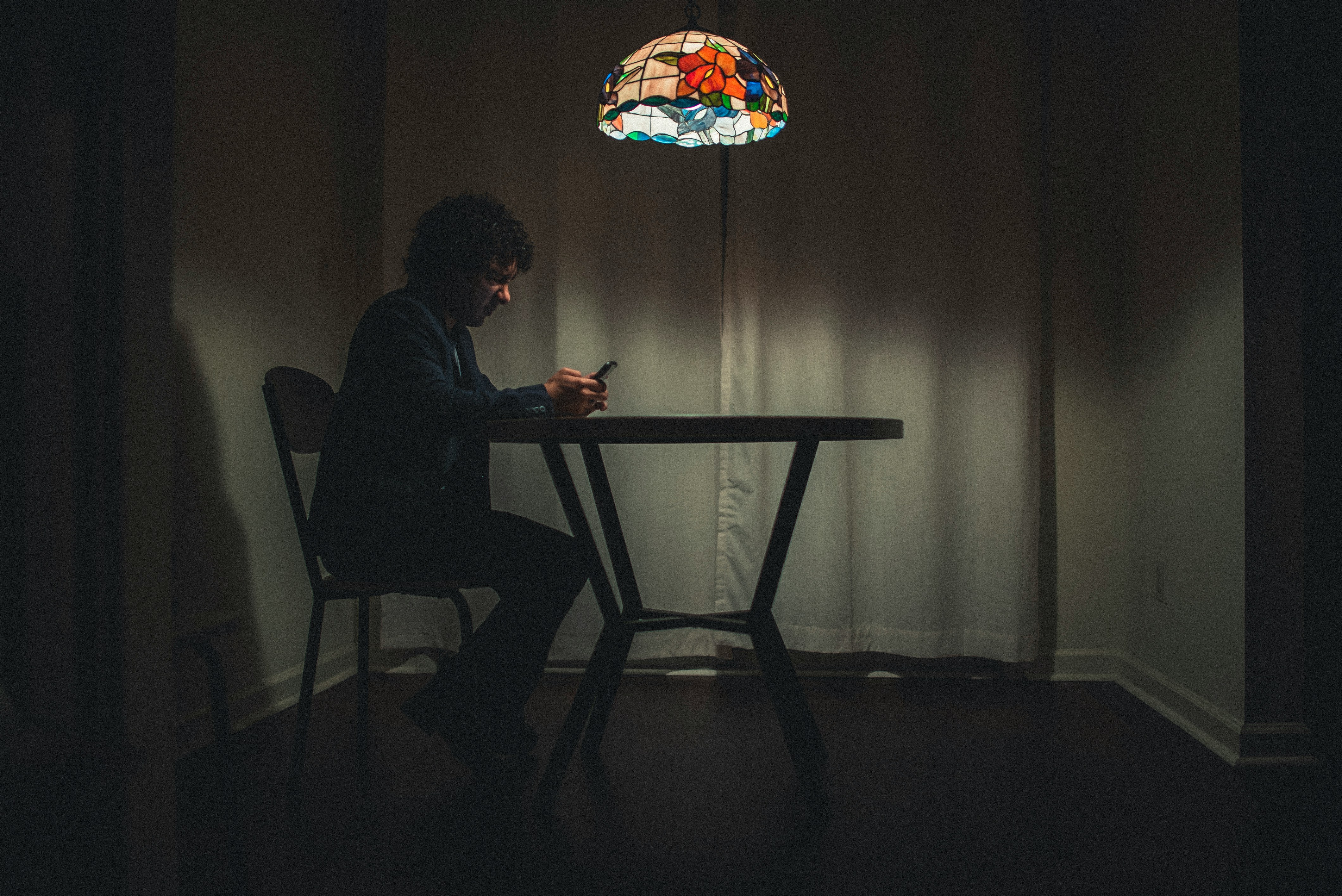 Un homme assis à une table et utilisant un téléphone portable | Source : Unsplash