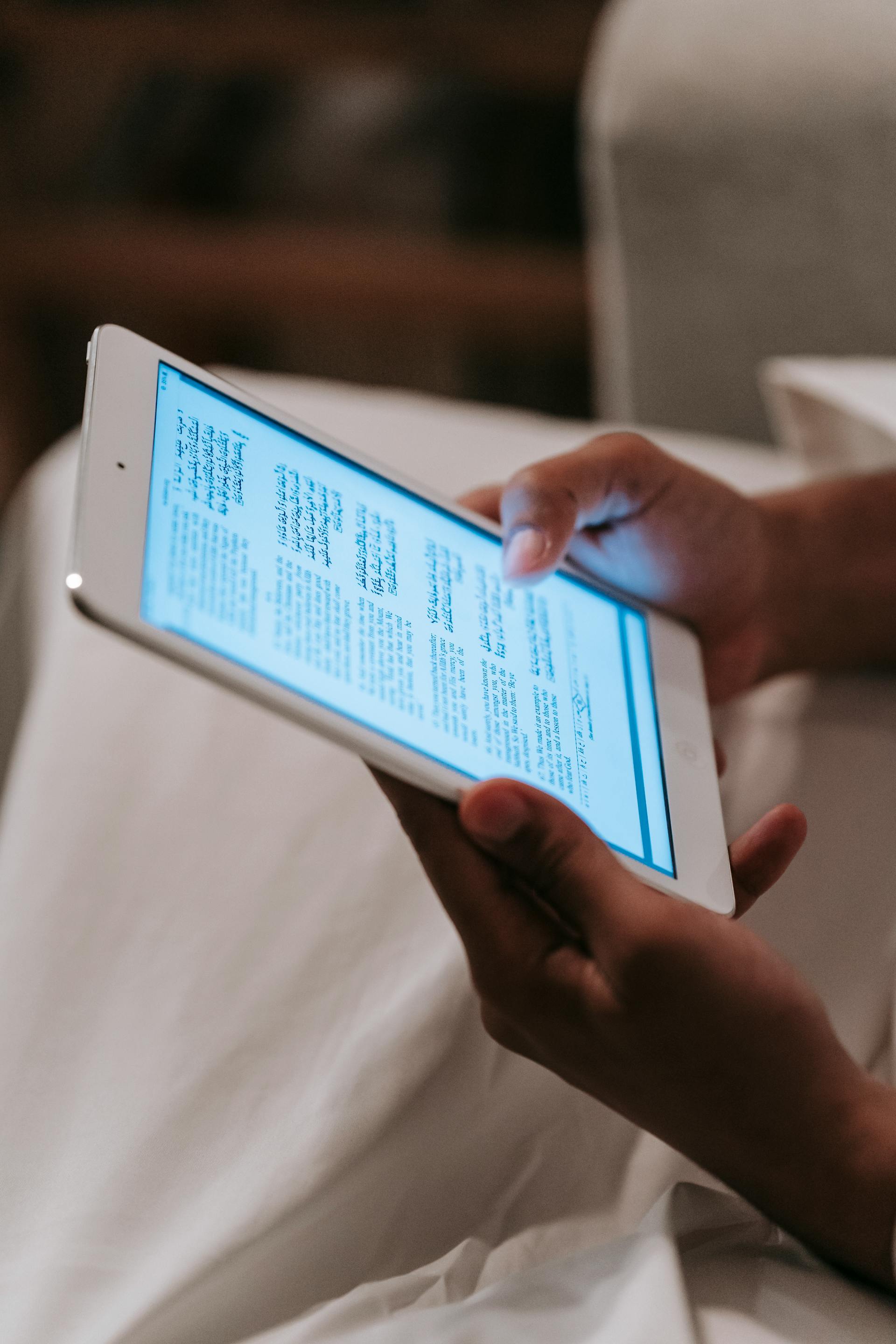 Une personne tenant et regardant une tablette avec un écran lumineux | Source : Pexels