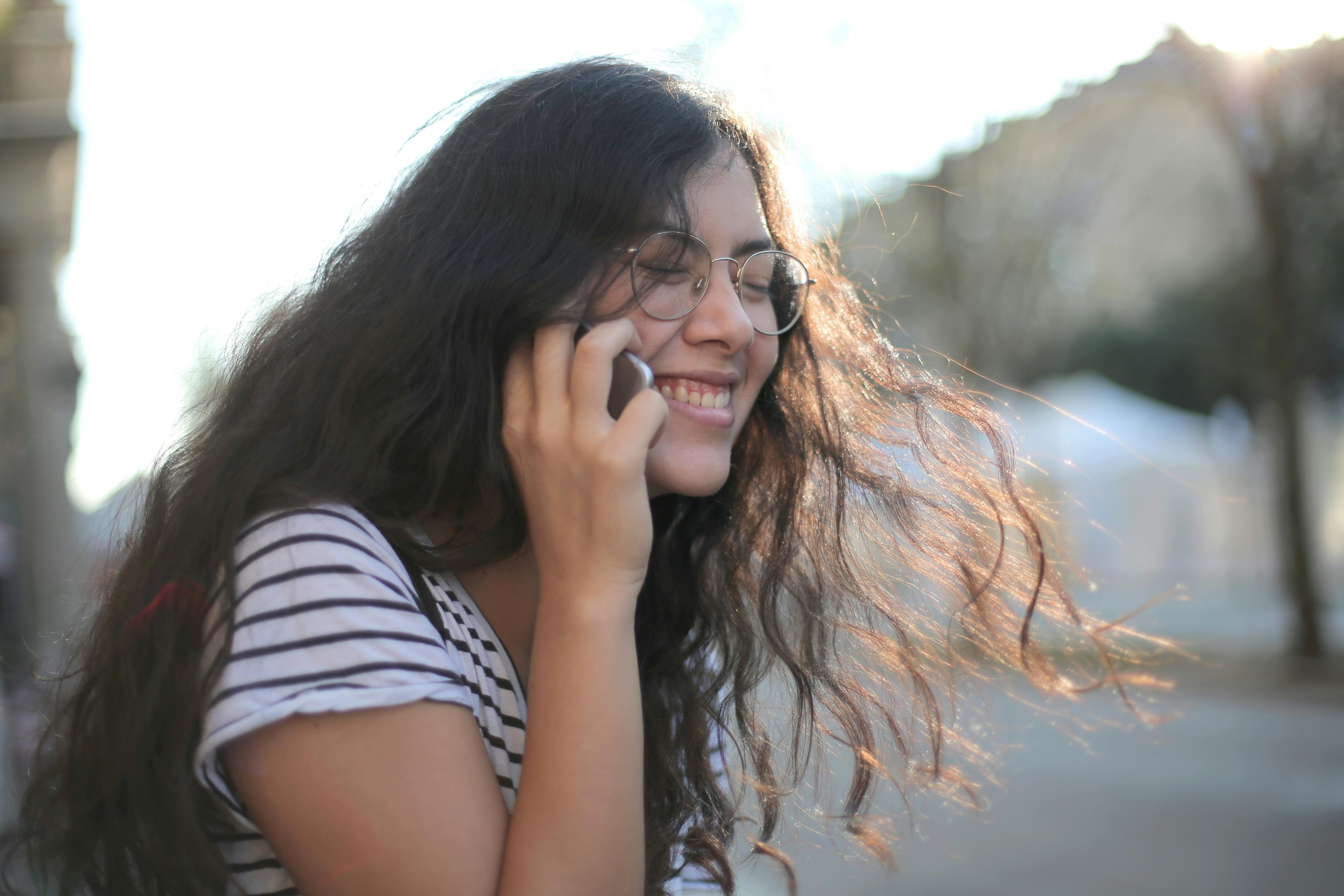 Une fille qui rit lors d'un appel téléphonique | Source : Pexels