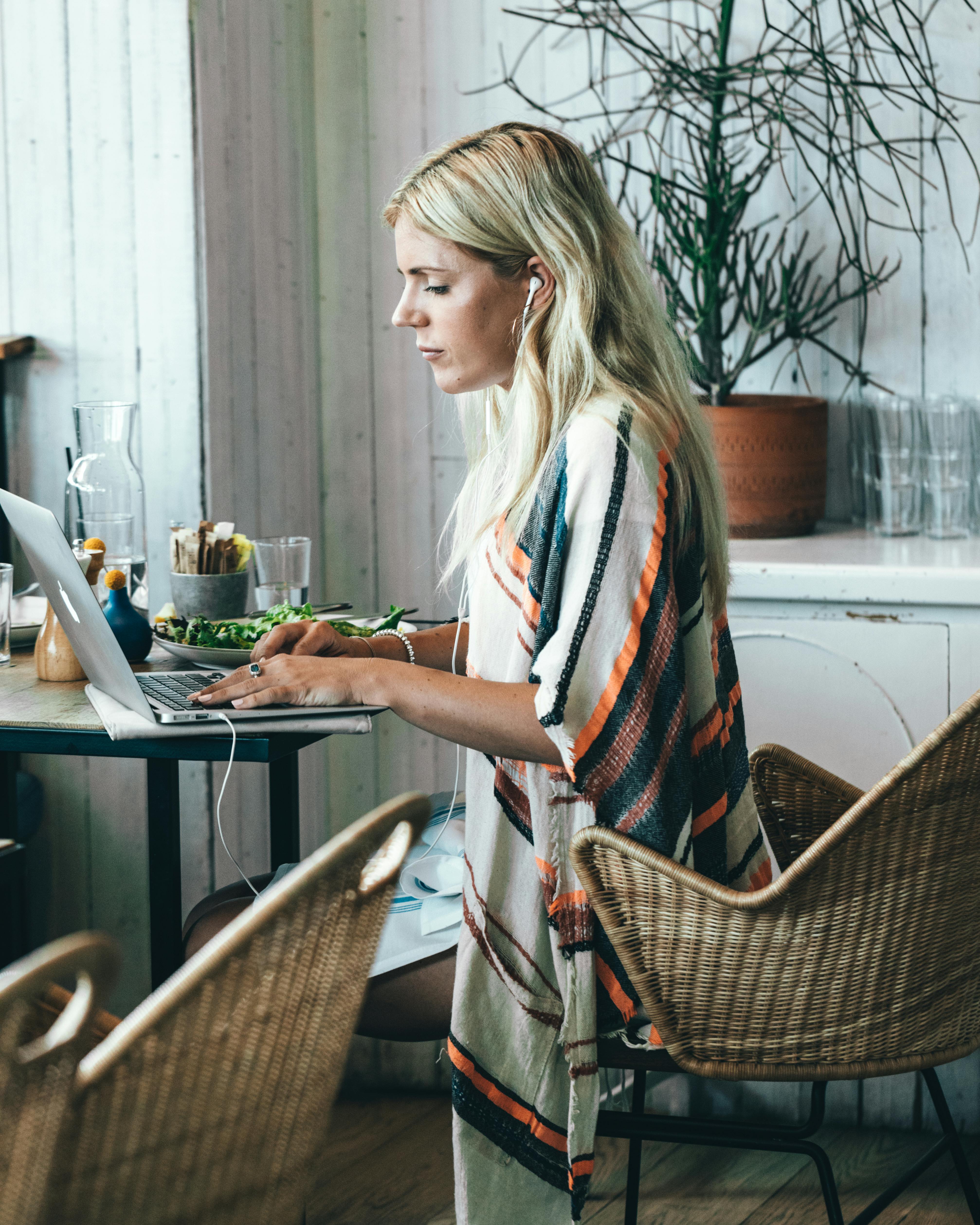 Une femme portant des écouteurs tout en utilisant un ordinateur portable | Source : Pexels