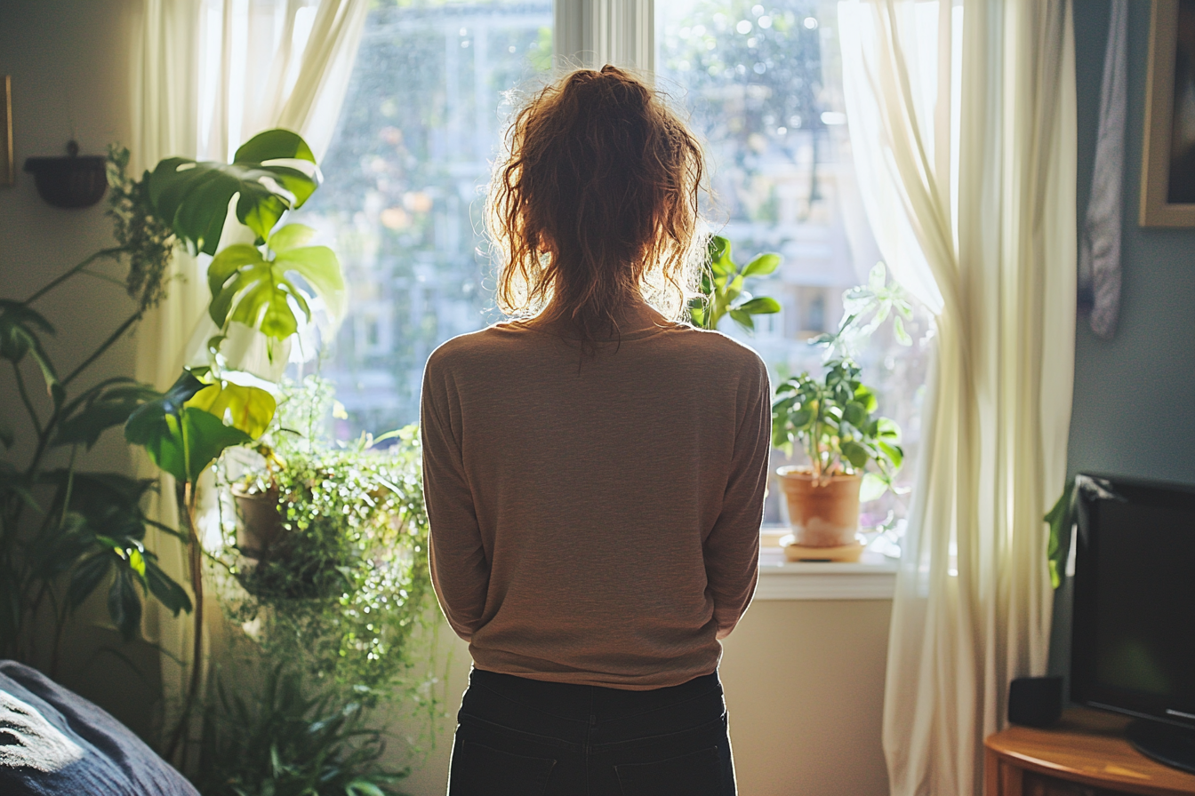 Une femme debout près d'une fenêtre | Source : Midjourney