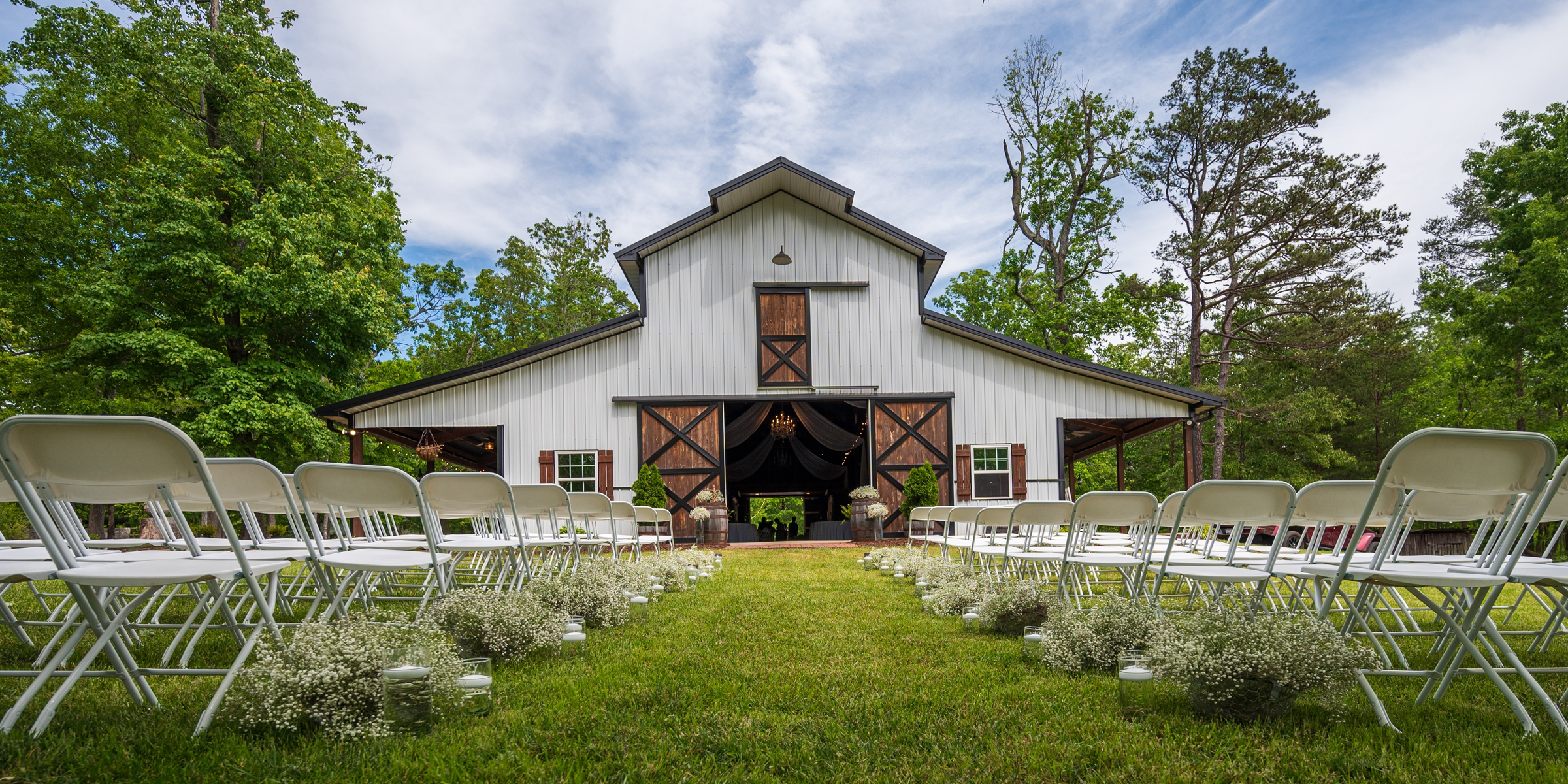 Un mariage rustique dans une grange avec des chaises blanches, des fleurs en forme de souffle de bébé et une charmante toile de fond de campagne | Source : Shutterstock