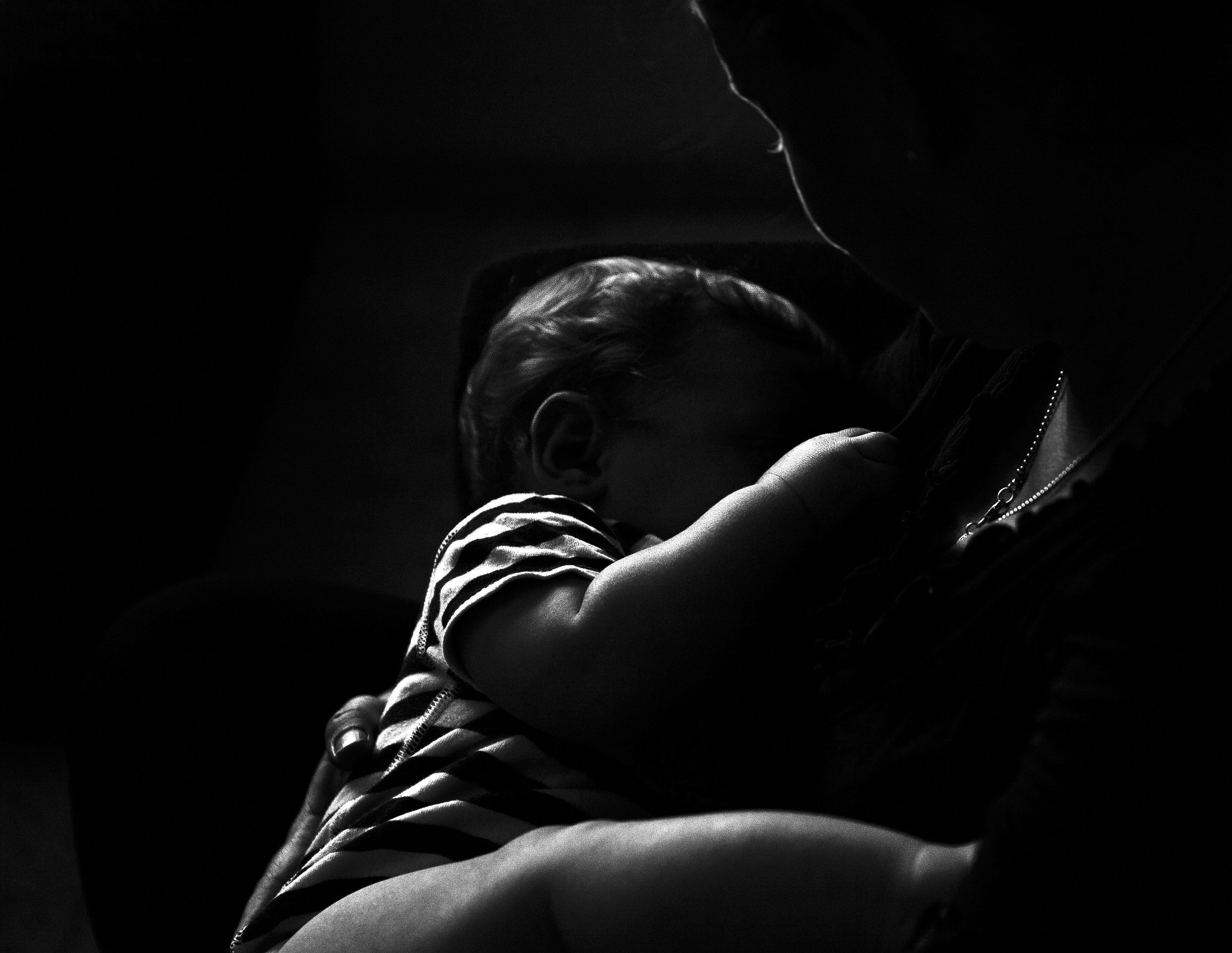 Une personne tenant un bébé dans l'obscurité | Source : Unsplash