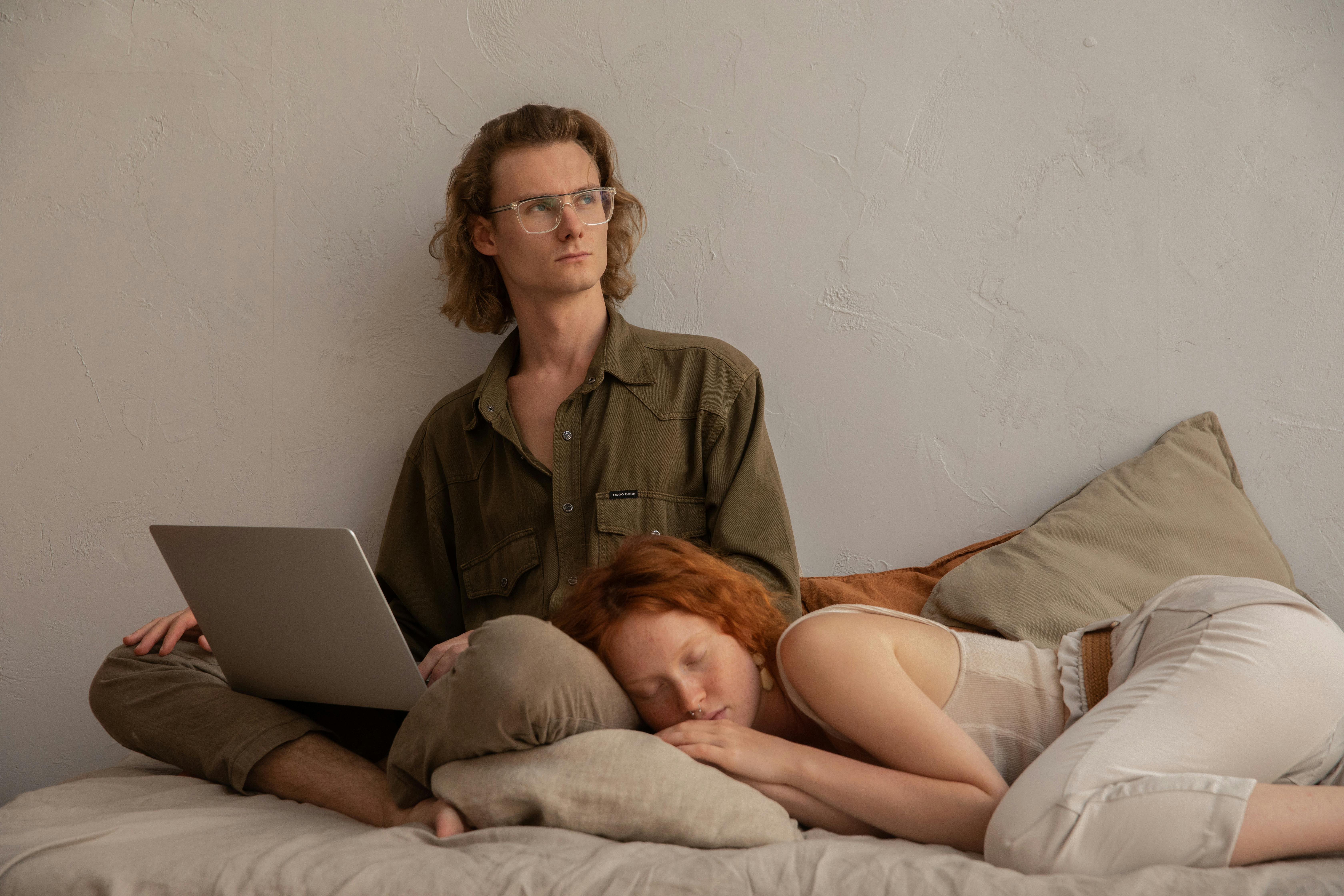 Un homme regarde sur le côté tandis qu'une femme dort à côté de lui | Source : Pexels