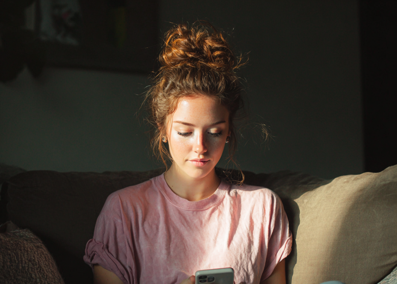 Une femme assise sur un canapé et utilisant son téléphone | Source : Midjourney