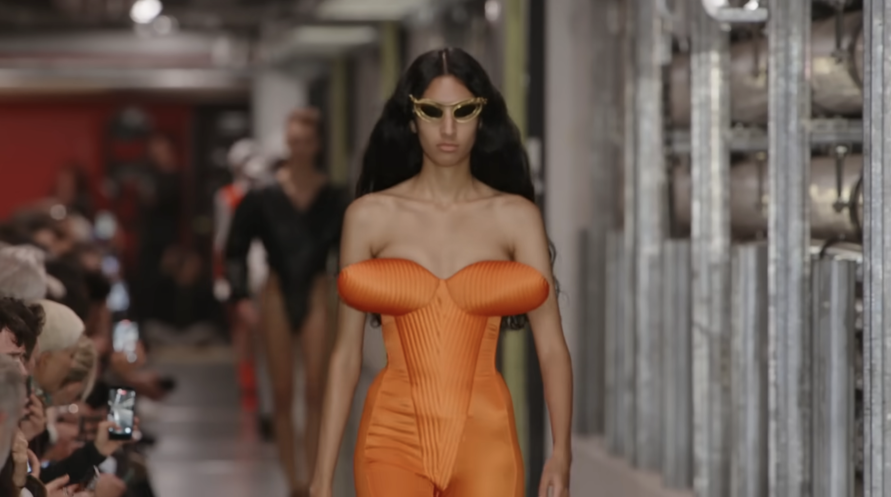 Duran Lantink a ouvert le défilé futuriste de la collection prêt-à-porter printemps-été 2026 de Jean Paul Gaultier avec des silhouettes pneumatiques. Ce look orange présente un soutien-gorge conique intégré à une combinaison à la structure unique. Extrait d'un post daté du 5 octobre 2025. Source : Youtube/@jeanpaulgaultier