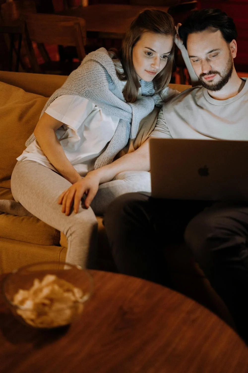 Un couple heureux qui regarde un film sur son canapé ⏐ Source : Pexels