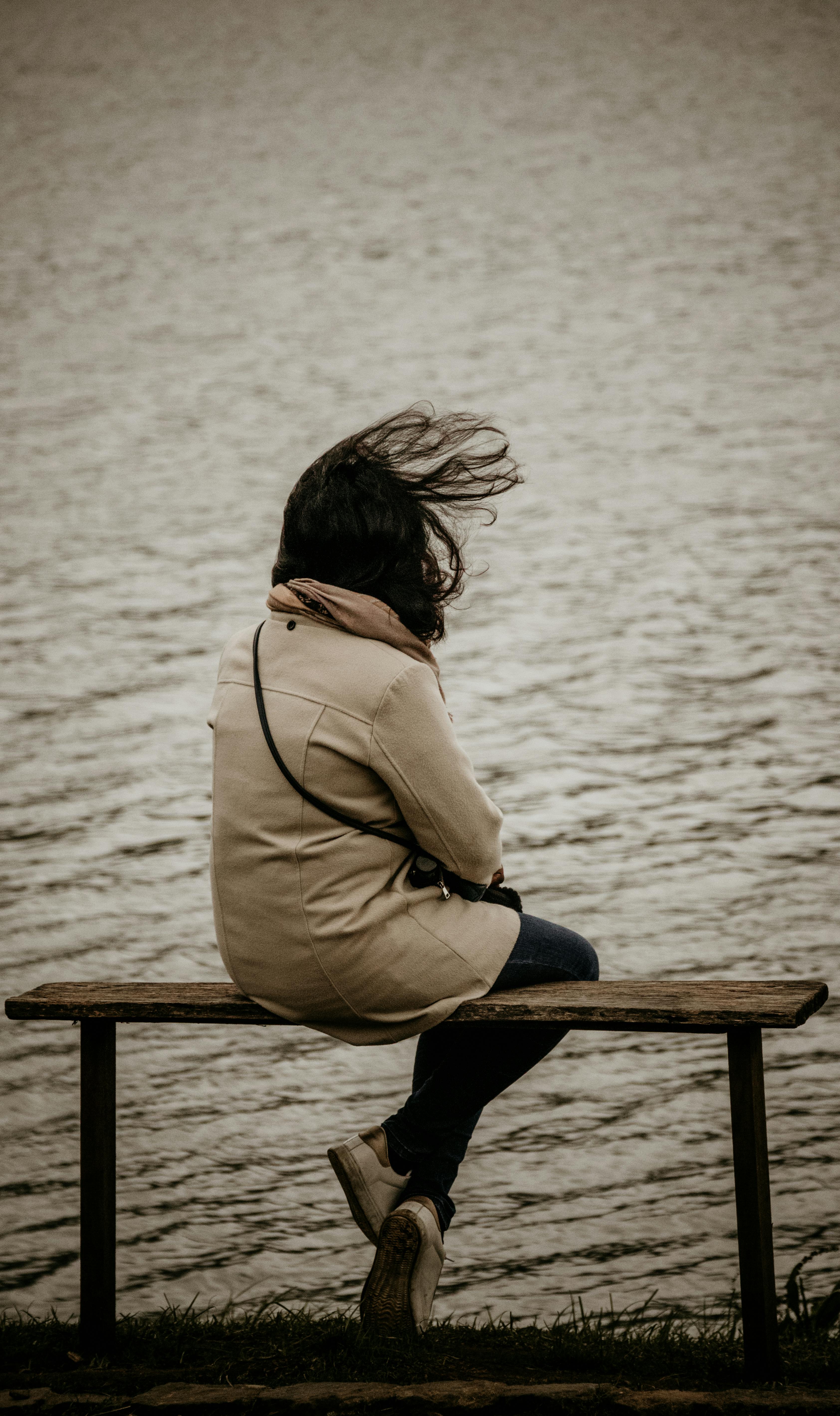 Une femme assise sur un banc au bord d'un lac | Source : Pexels