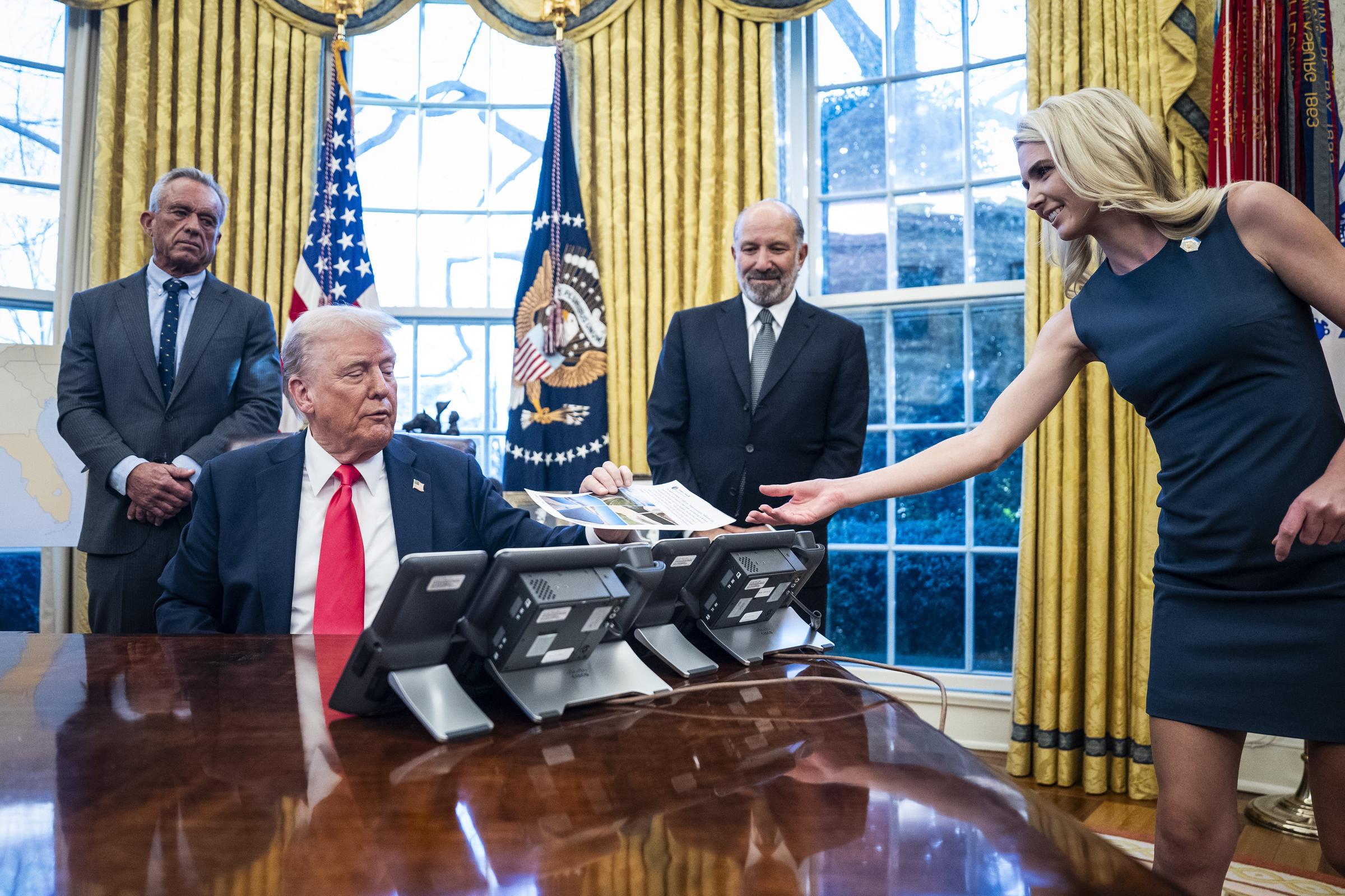 Donald Trump est assis au bureau « Resolute » tandis que sa collaboratrice Natalie Harp lui tend des documents lors d'une réunion à la Maison Blanche en 2025. Son rôle de collaboratrice chargée de transmettre directement les informations au président a joué un rôle central dans la proximité inhabituelle qu'elle entretenait avec lui — et a fini par contribuer à lui valoir le surnom que ses collègues lui avaient donné. | Source : Getty Images
