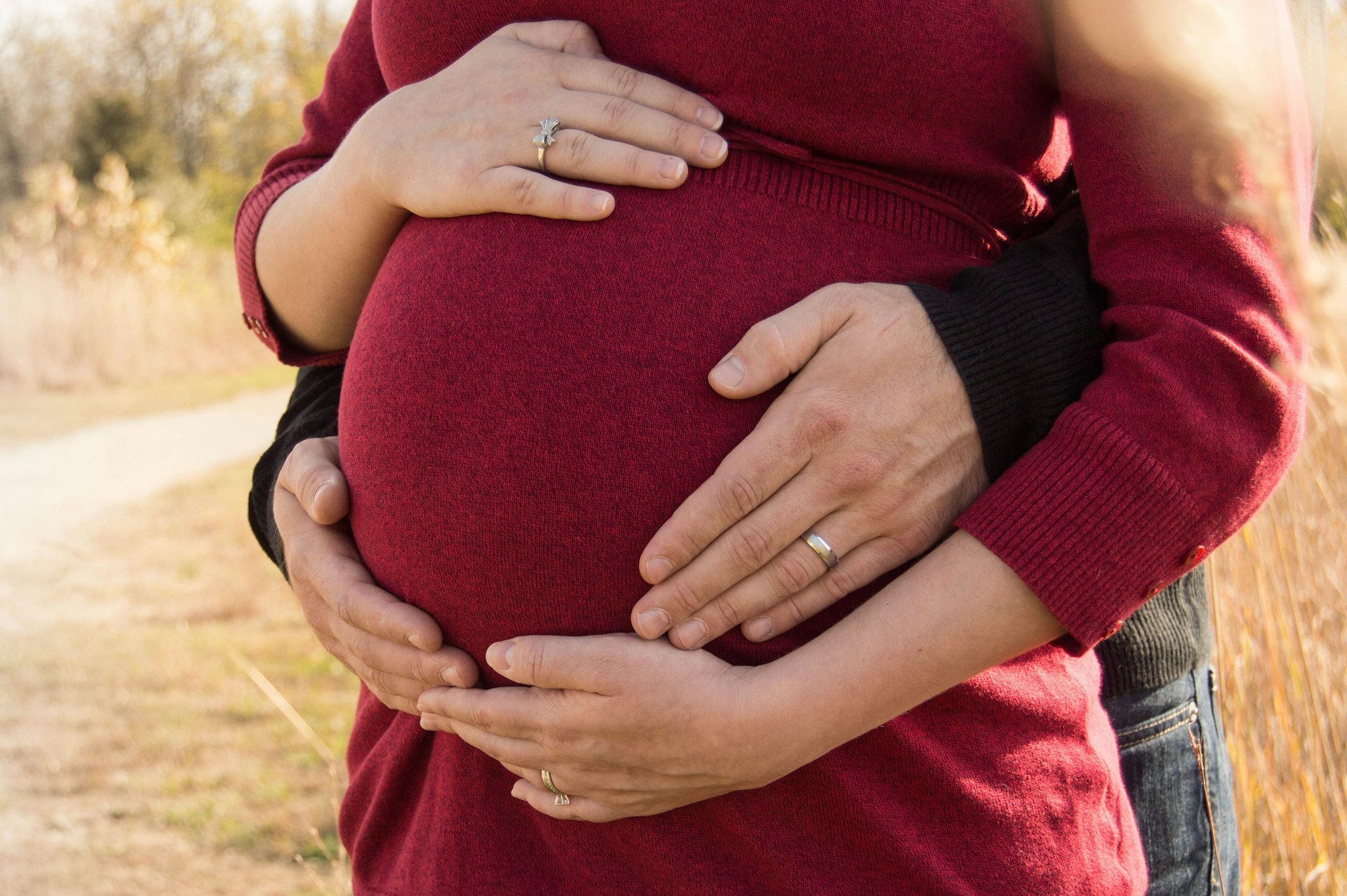 Un homme tenant sa partenaire enceinte par derrière | Source : Unsplash