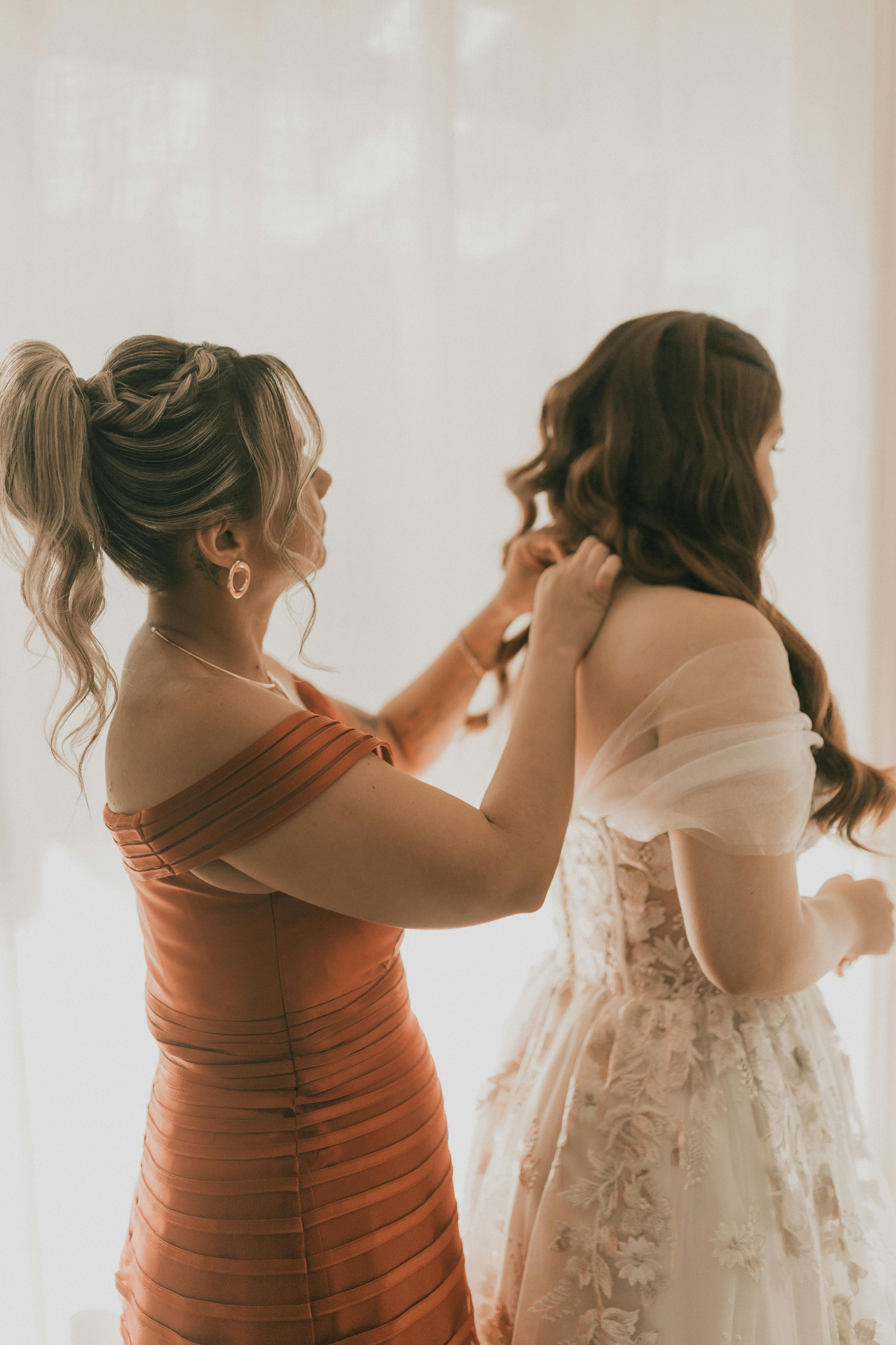 Une demoiselle d'honneur aidant une mariée | Source : Pexels