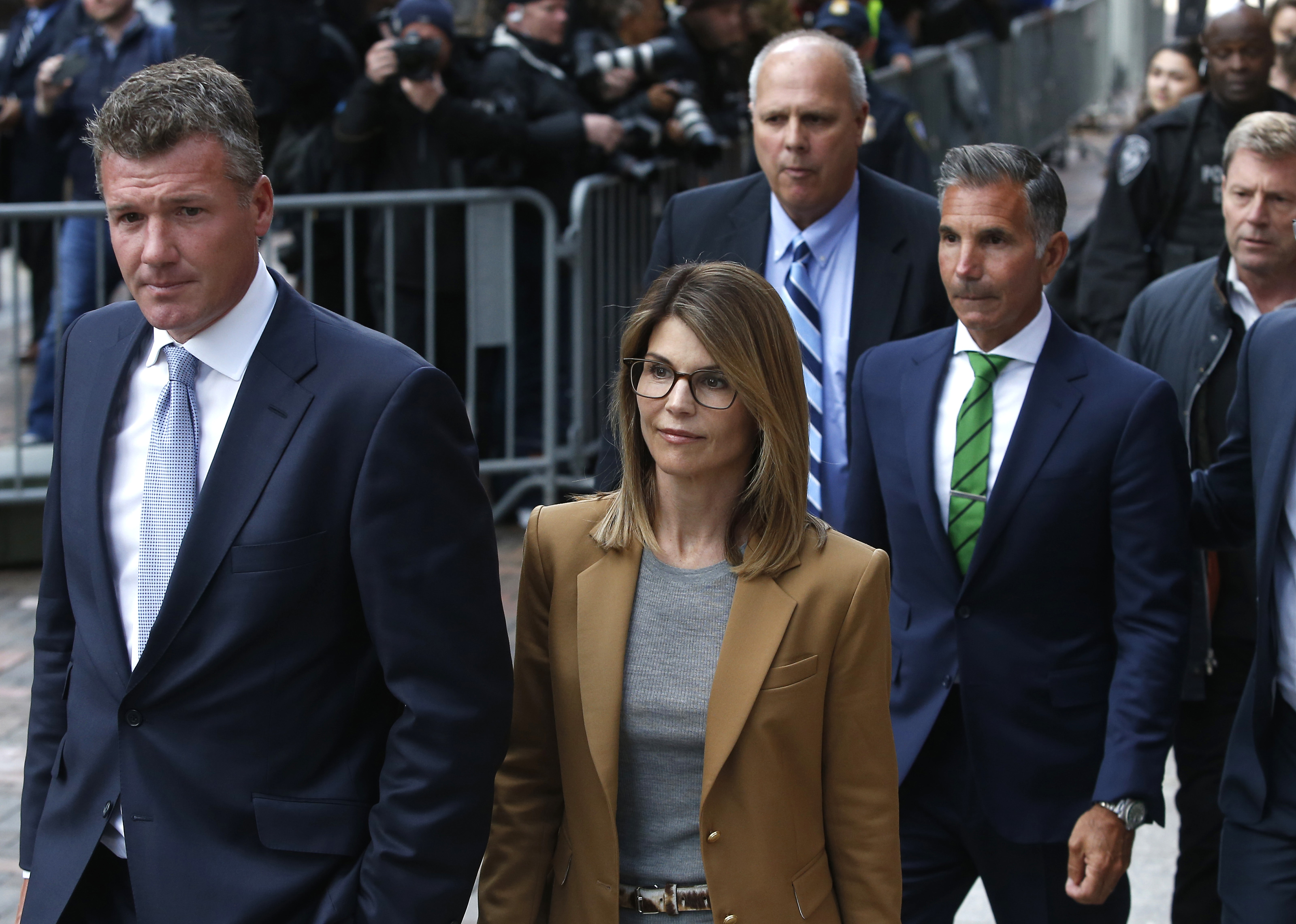 Lori Loughlin, en manteau fauve, quitte le tribunal fédéral de Boston avec son mari Mossimo Giannulli, en cravate verte, le 3 avril 2019 | Source : Getty Images