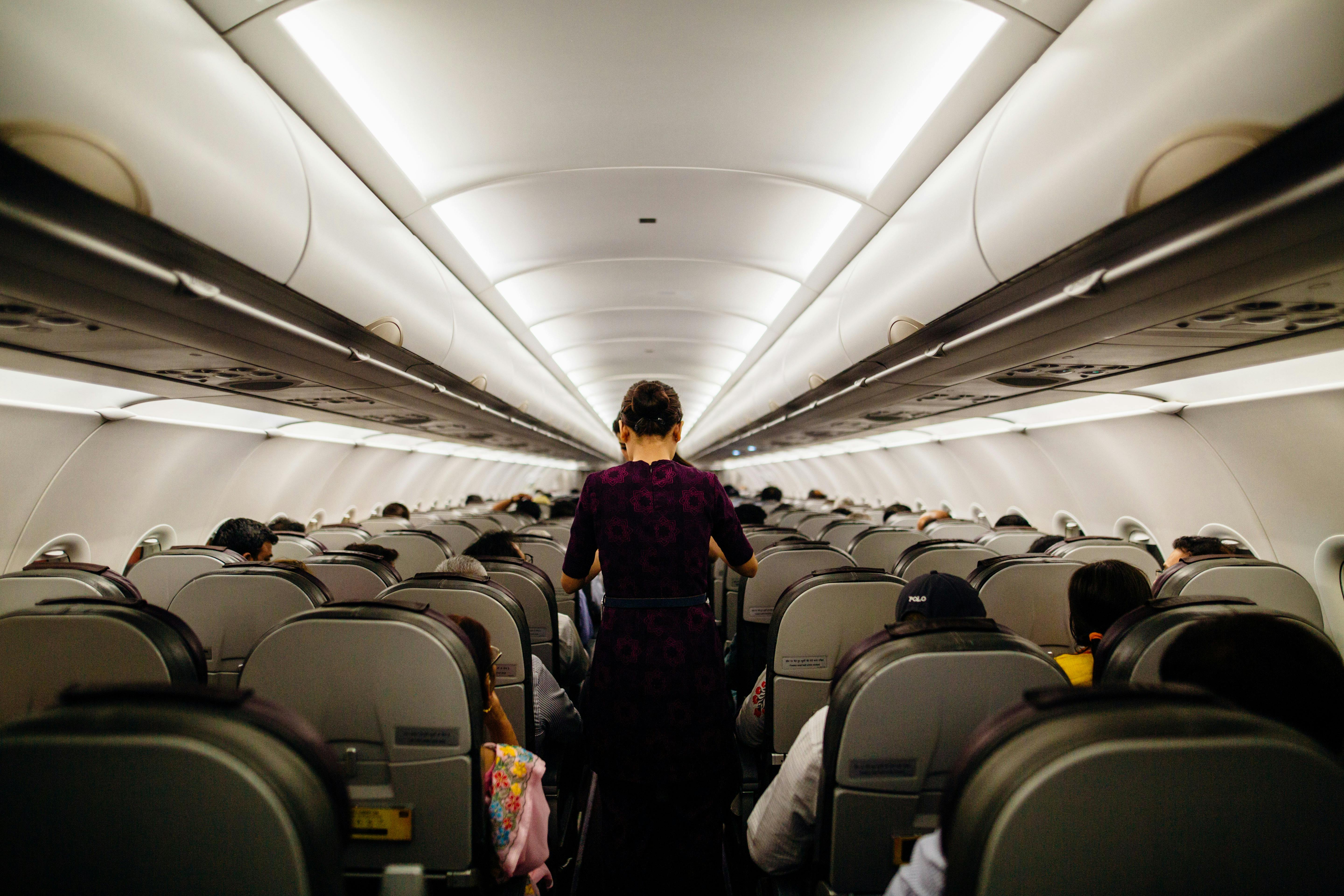 Une hôtesse de l'air debout dans une allée d'avion | Source : Pexels