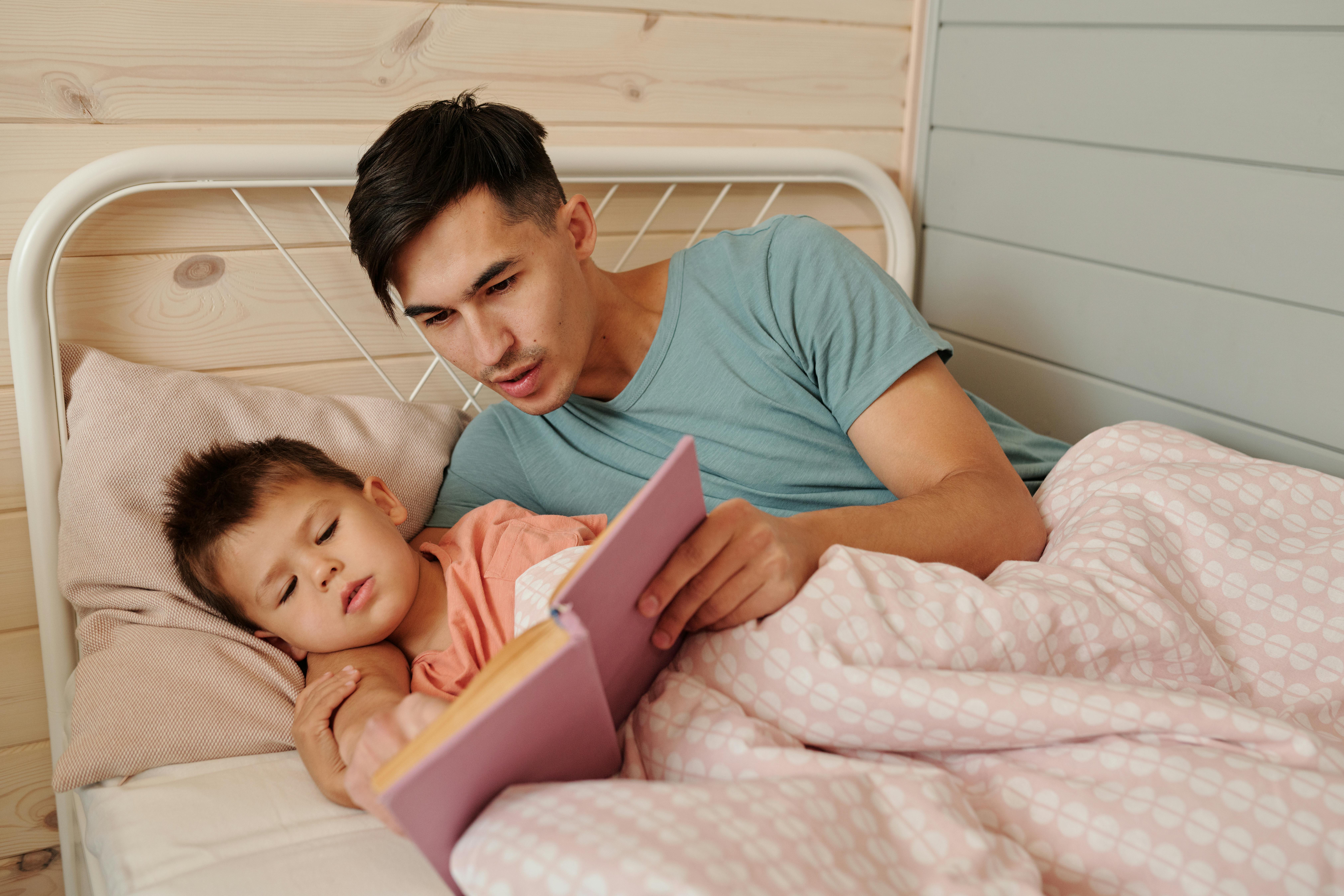 Un homme lisant une histoire à l'heure du coucher à un enfant | Source : Pexels