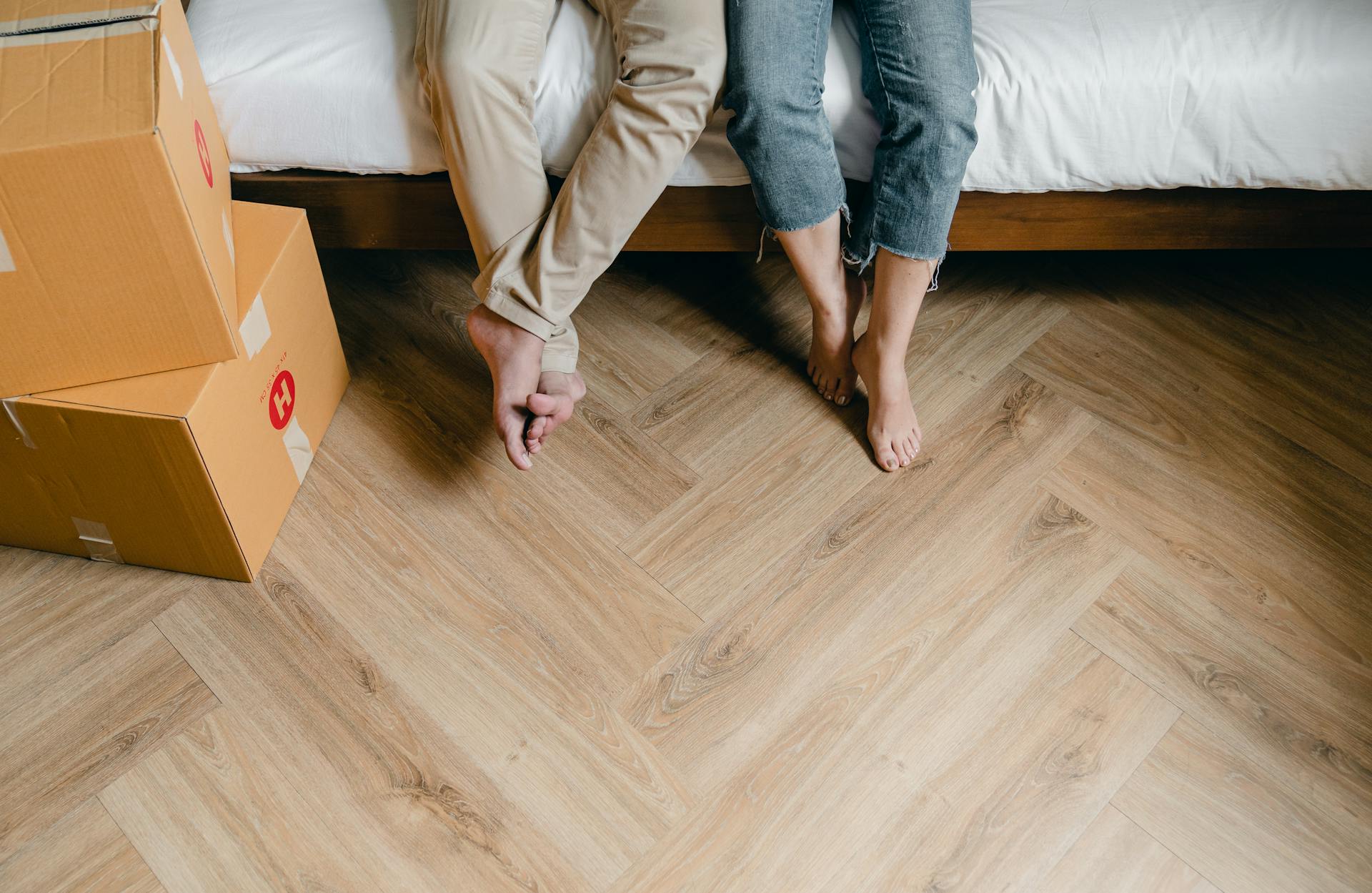 Un couple assis sur le lit avec des boîtes en carton autour d'eux | Source : Pexels