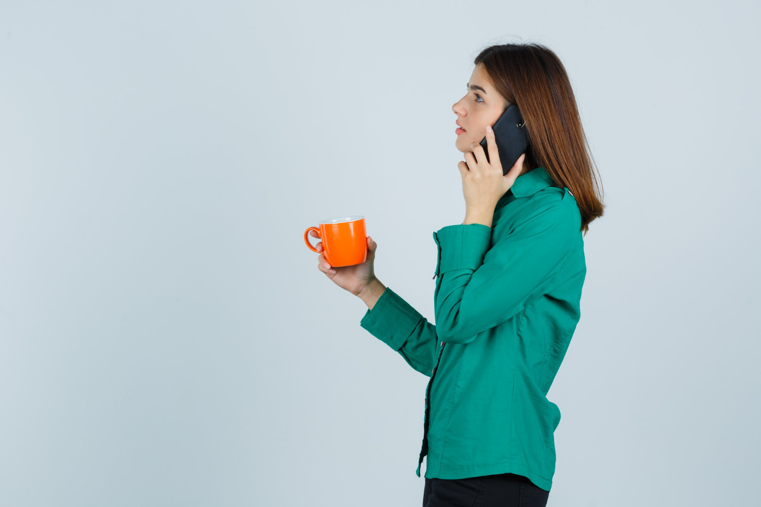 Une femme tenant une tasse orange et parlant au téléphone | Source : Freepik