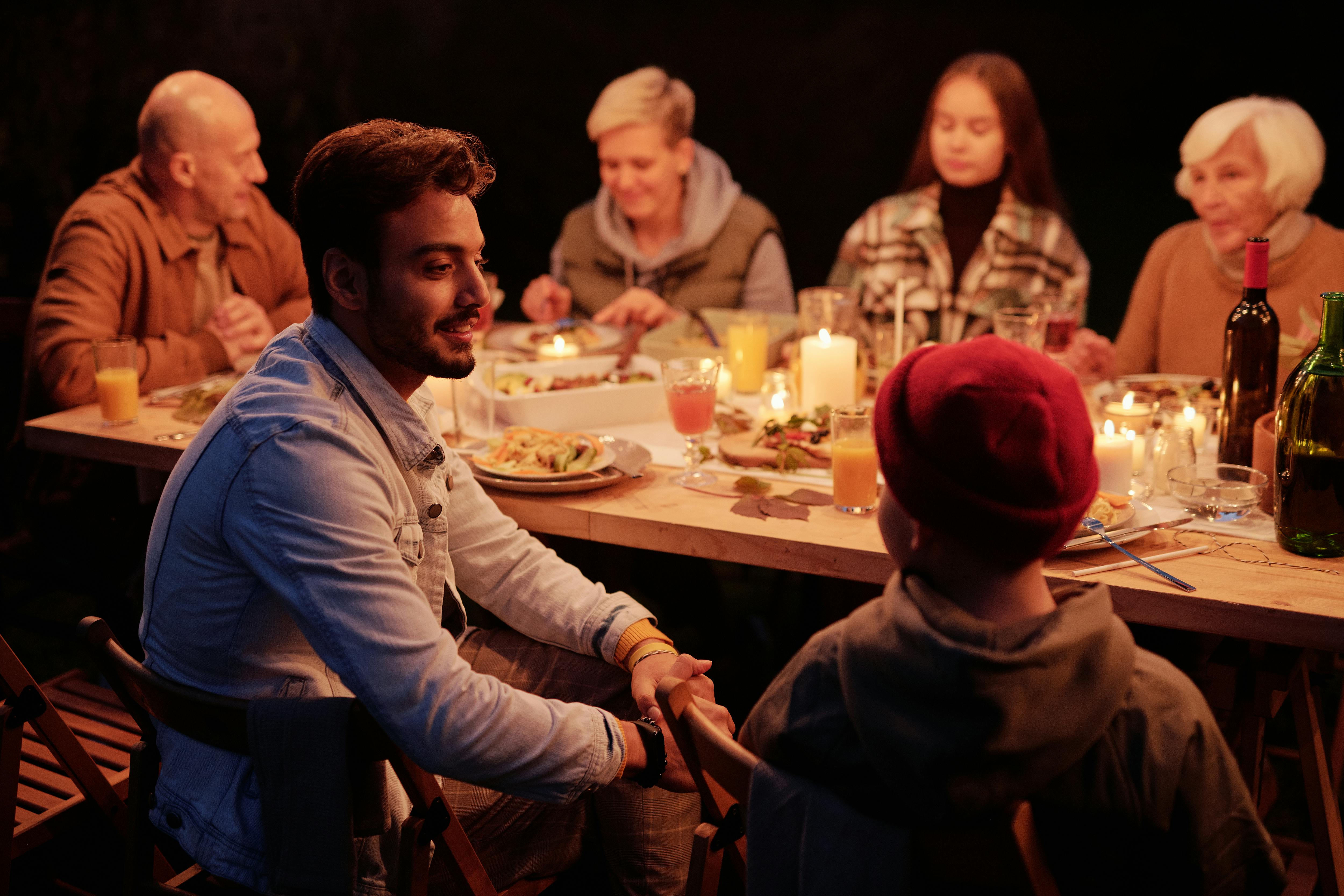 Des gens se réunissent pour dîner dans un jardin de nuit et discutent | Source : Pexels