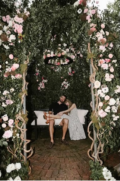 Taylor Swift et Travis Kelce assis sur un banc sous une arche de fleurs après s'être fiancés, extrait de son post daté du 26 août 2025 | Source : Instagram/taylorswift