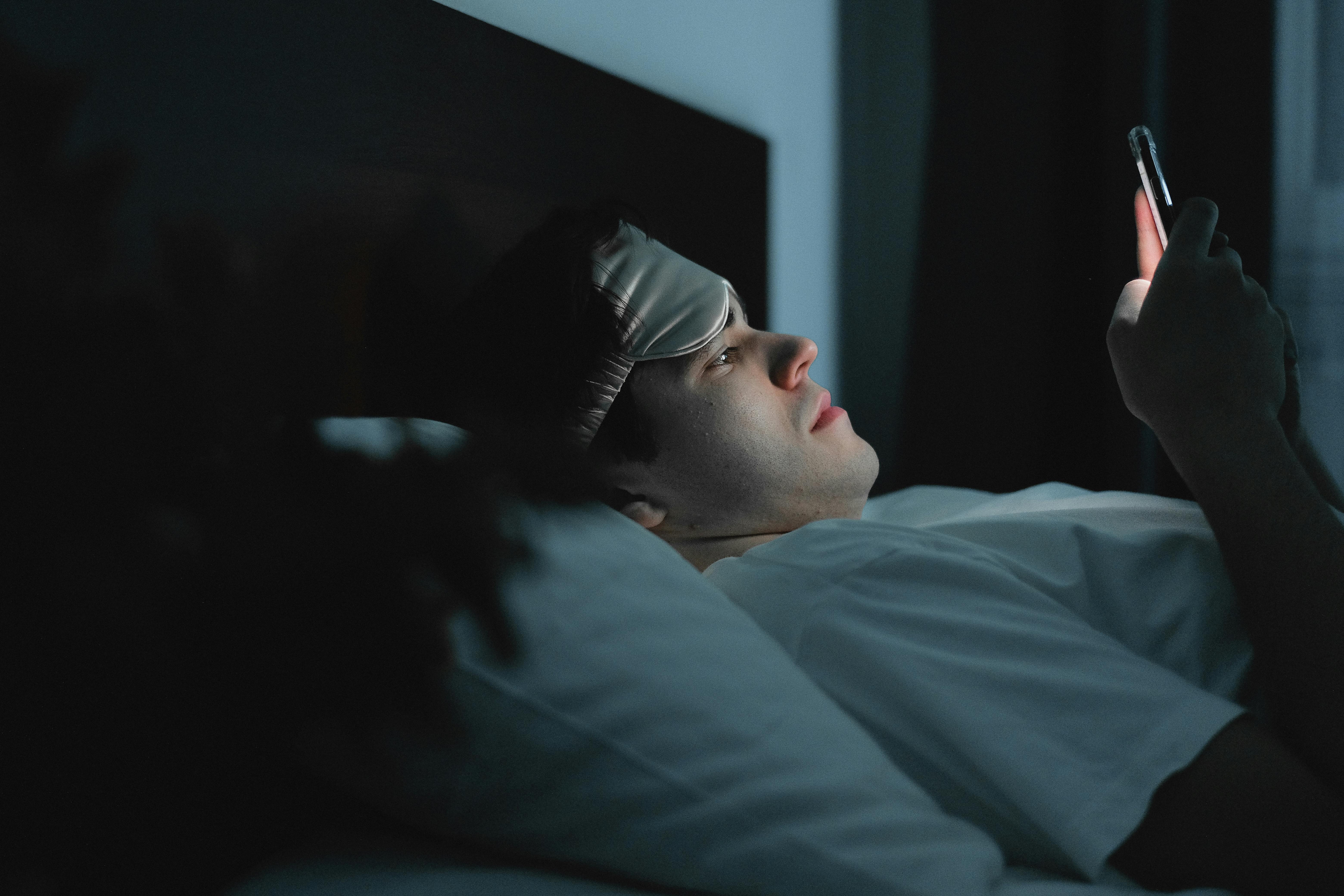 Un homme utilisant son téléphone dans l'obscurité | Source : Pexels