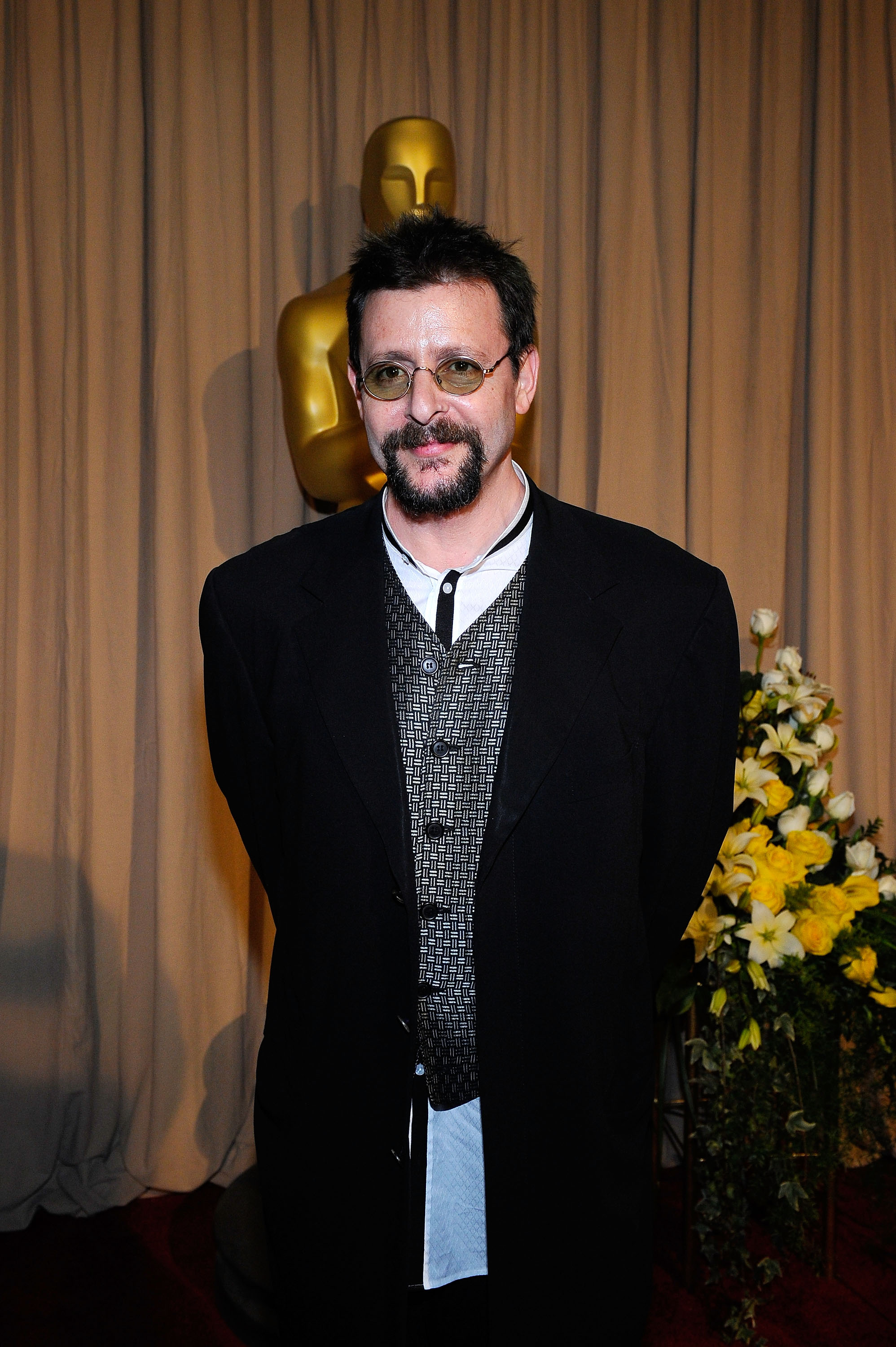 En coulisses, près d'une statuette dorée des Oscars, lors de la 82e cérémonie des Oscars le 7 mars 2010, l'acteur portait un gilet à motifs et un manteau foncé, avec de petites lunettes teintées et une barbichette soigneusement taillée. | Source : Getty Images
