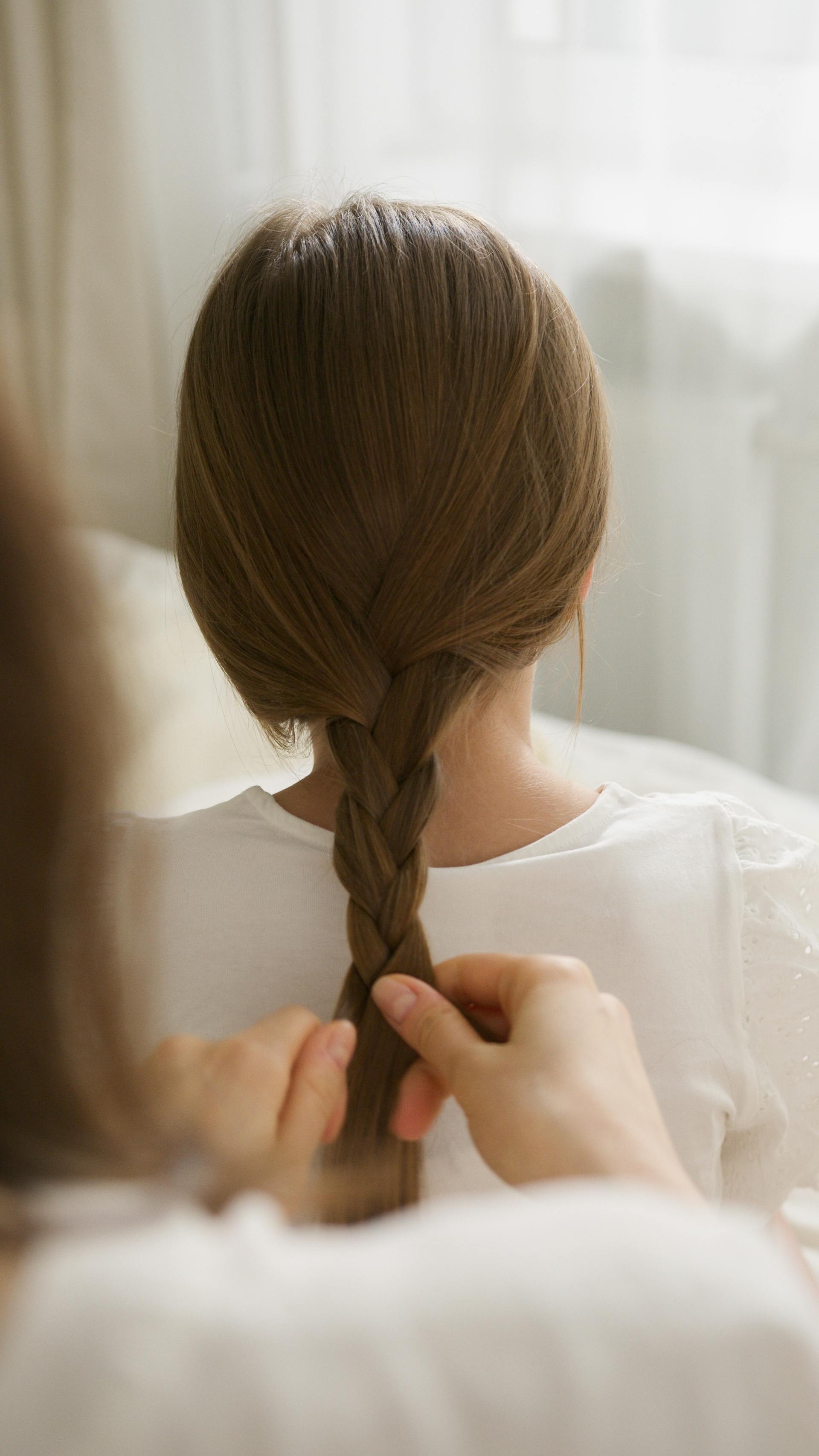 Gros plan sur une femme qui tresse les cheveux de sa fille | Source : Pexels