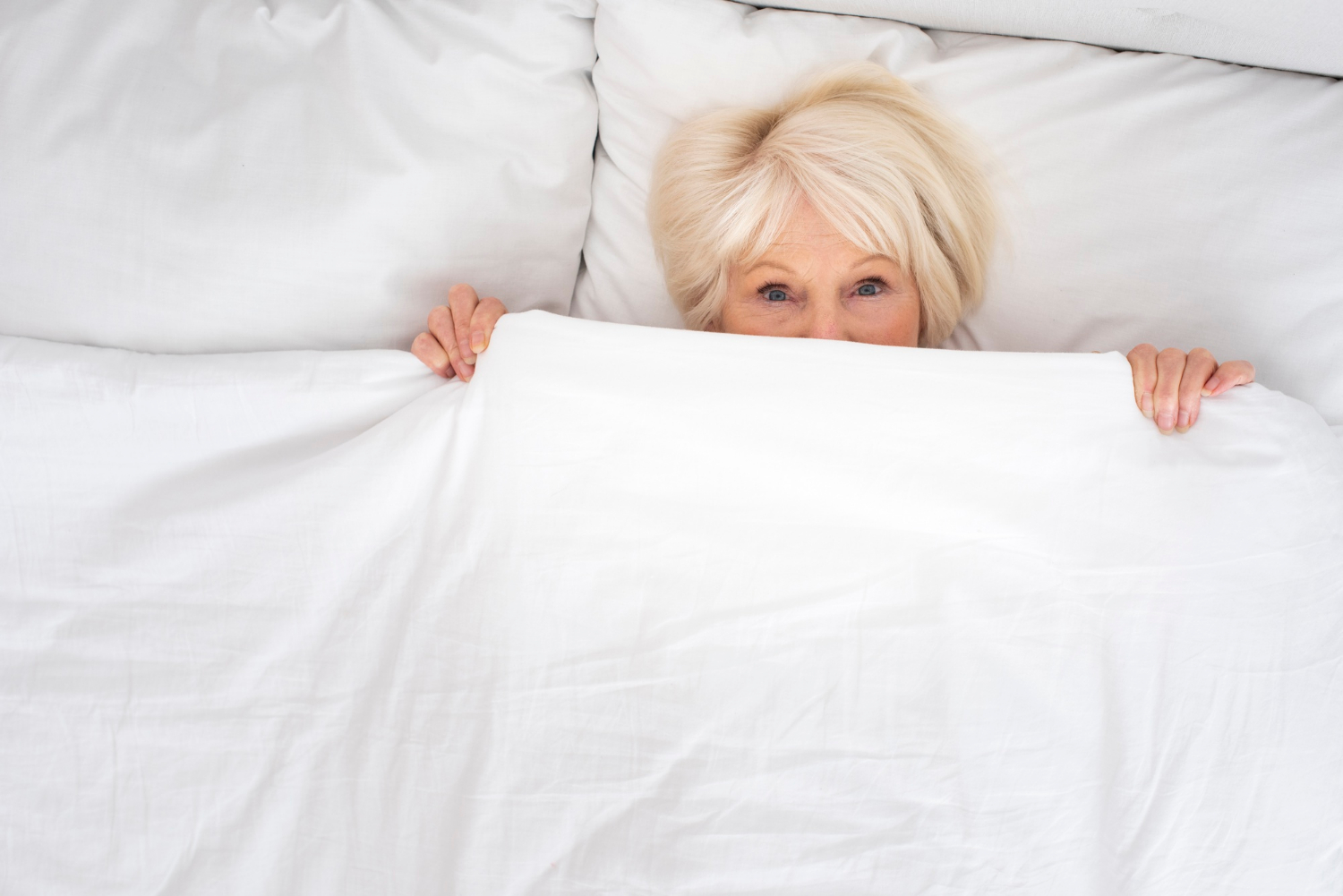 Une femme âgée effrayée, allongée dans son lit | Source : Freepik