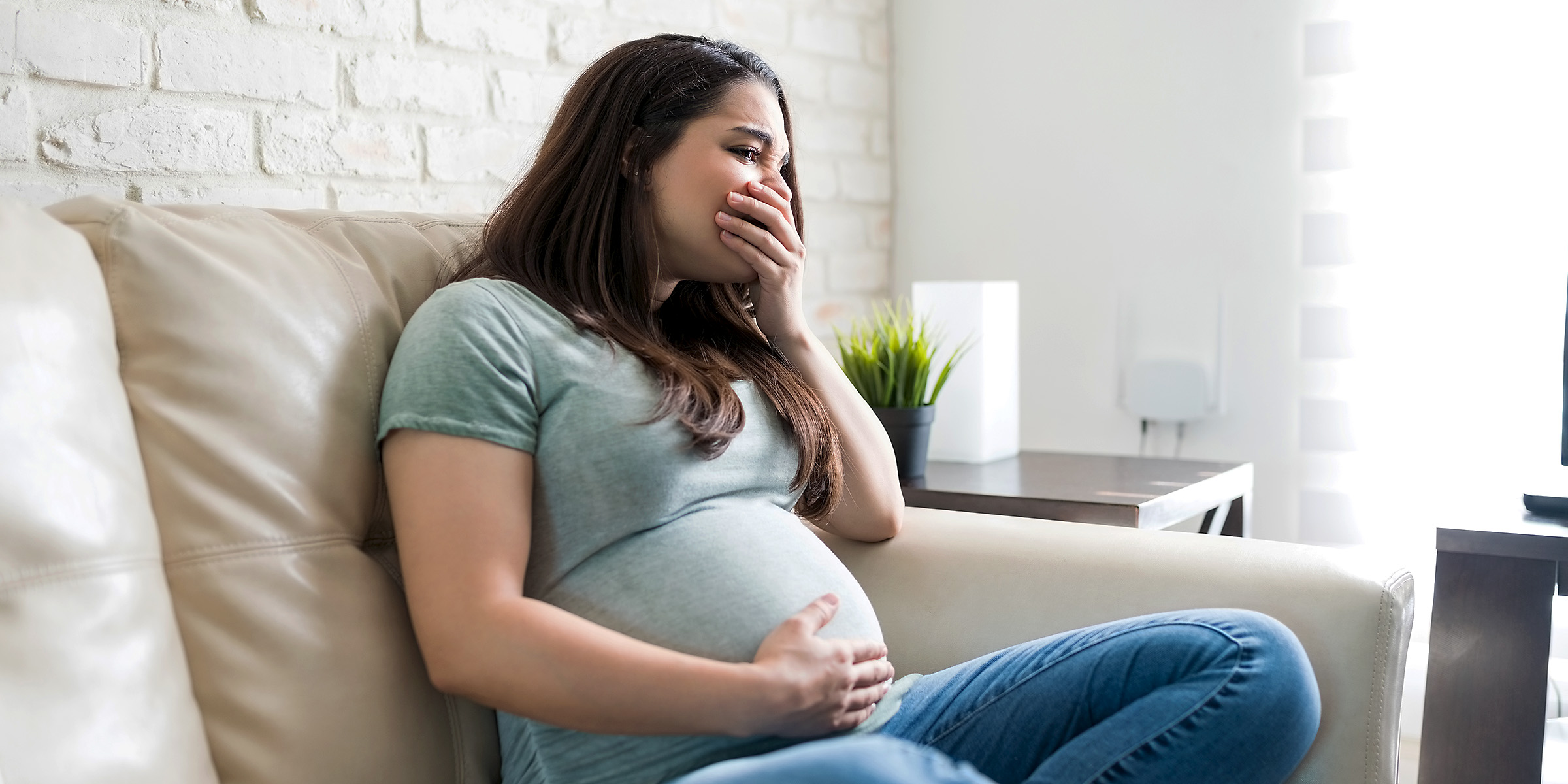 Une femme enceinte contrariée assise sur un canapé | Source : Shutterstock