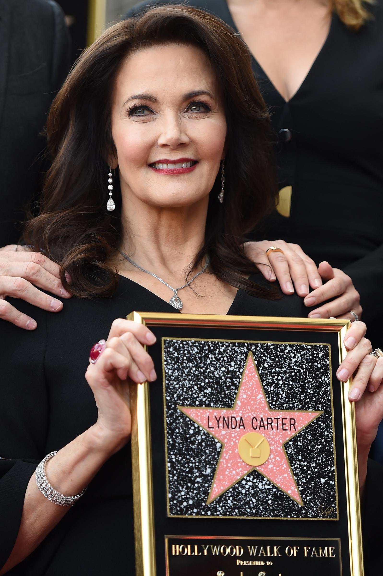 Lynda Carter rayonne de fierté alors qu'elle tient sa plaque du Hollywood Walk of Fame lors de la cérémonie d'inauguration. Vêtue d'un élégant ensemble noir, parée de délicats bijoux en argent et de boucles d'oreilles pendantes, elle célèbre cette étape importante de sa carrière entourée de ses proches, affichant toute sa grâce habituelle.