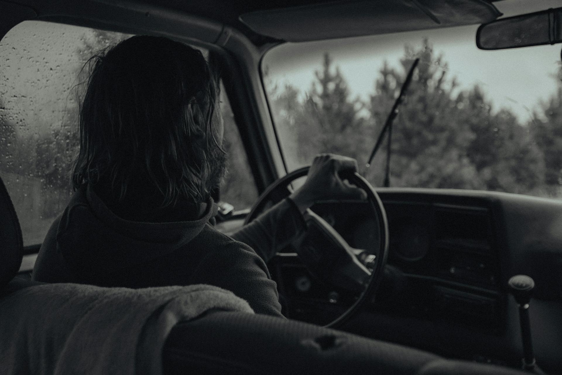 Photo en niveaux de gris d'une femme conduisant une voiture sous la pluie | Source : Pexels