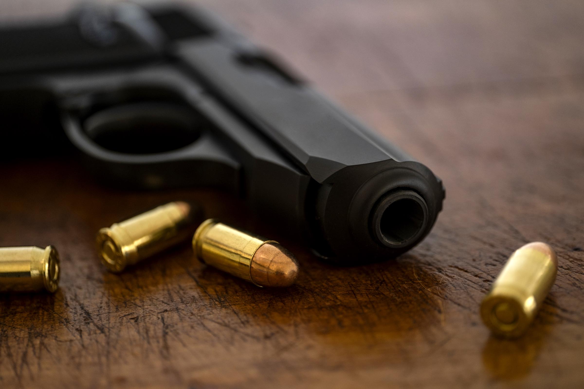 Balles et pistolet sur une surface en bois I Photo d'illustration I Source : Getty Images