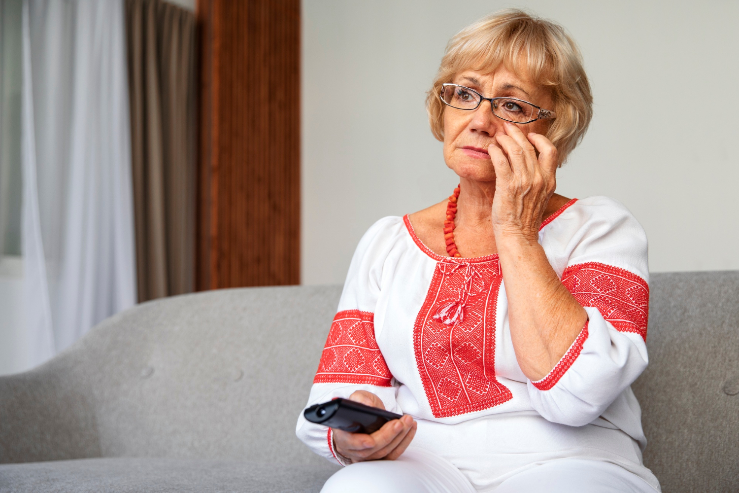 Une femme âgée triste tenant une télécommande | Source : Freepik