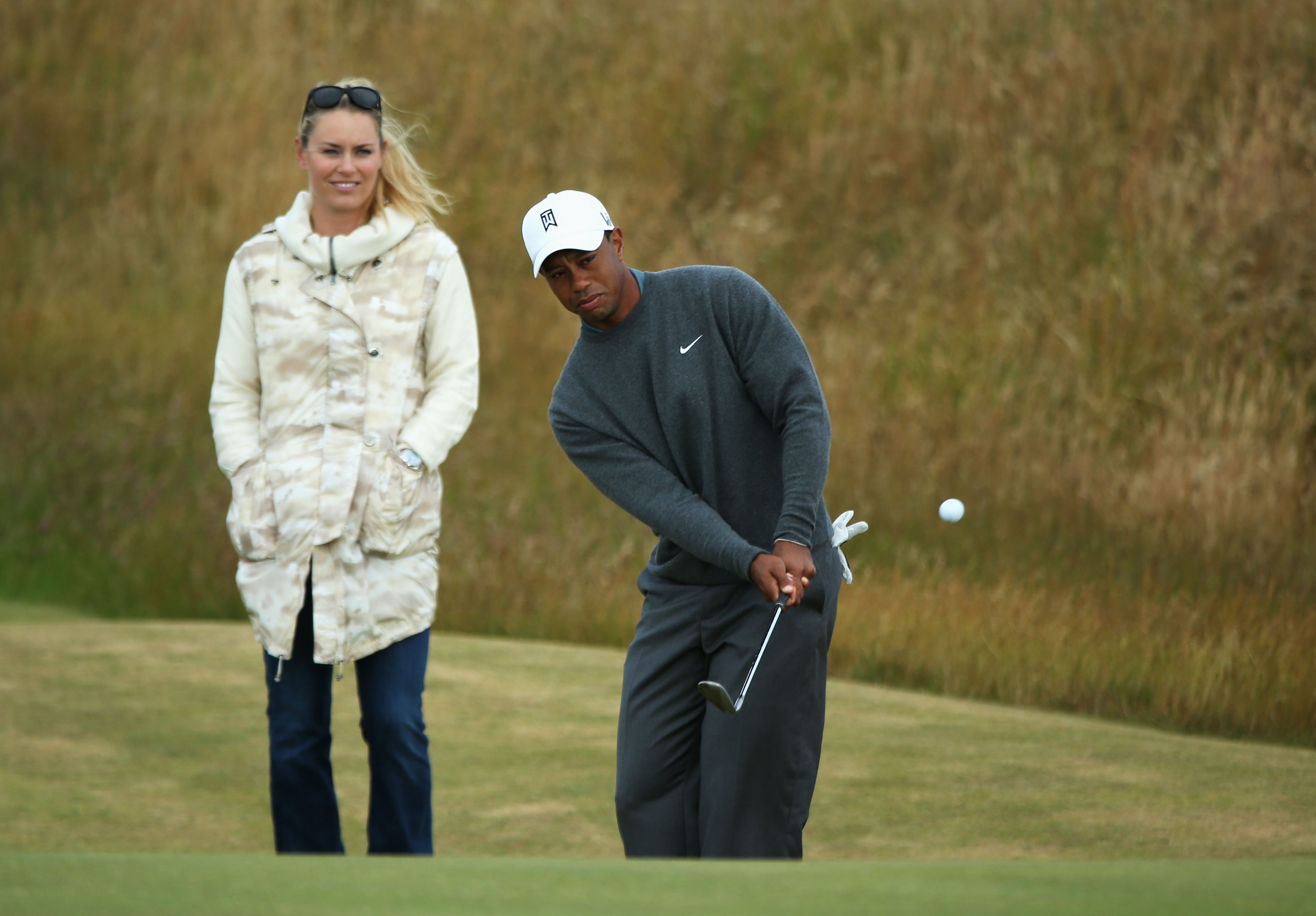 Tiger Woods envoie la balle en chips sous le regard de Lindsey Vonn lors du 142e Open Championship, le 15 juillet 2013, à Gullane, en Écosse | Source : Getty Images