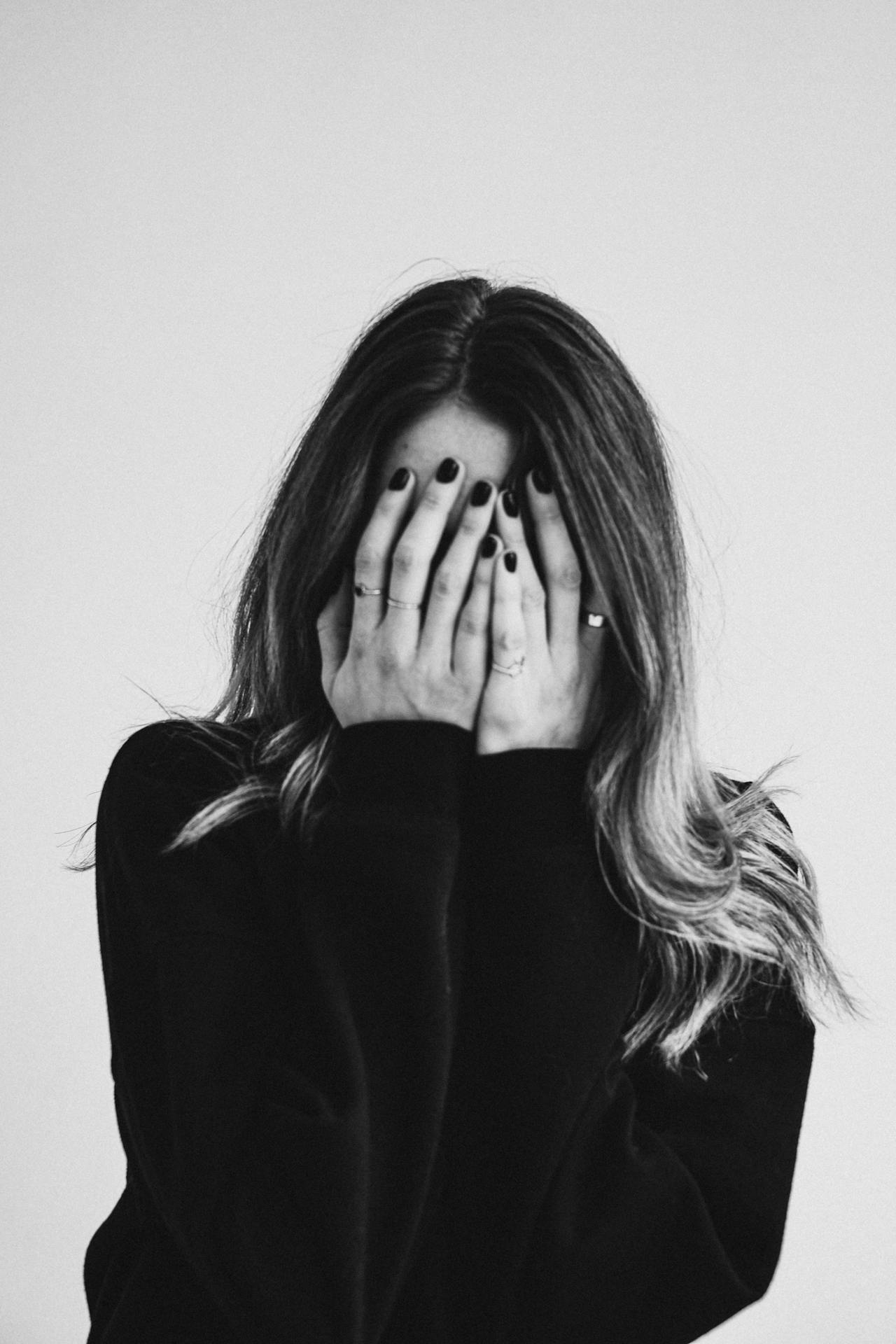 Prise de vue en niveaux de gris d'une femme triste se couvrant le visage | Source : Pexels