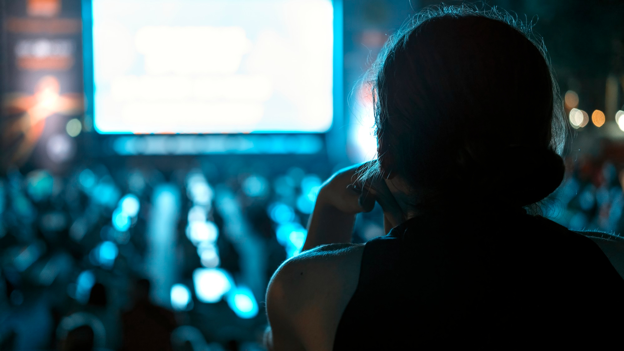 Une femme qui regarde les gens regarder quelque chose sur un écran lors d'un événement | Source : Freepik