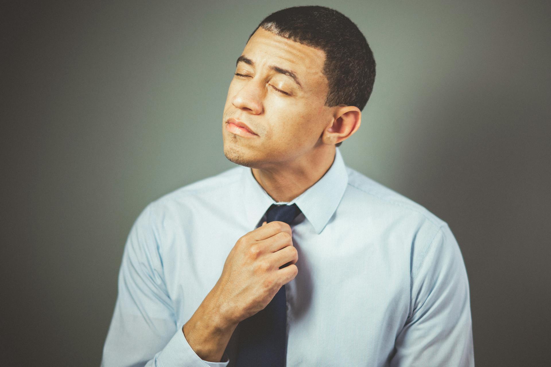 Un homme malheureux tenant sa cravate | Source : Pexels