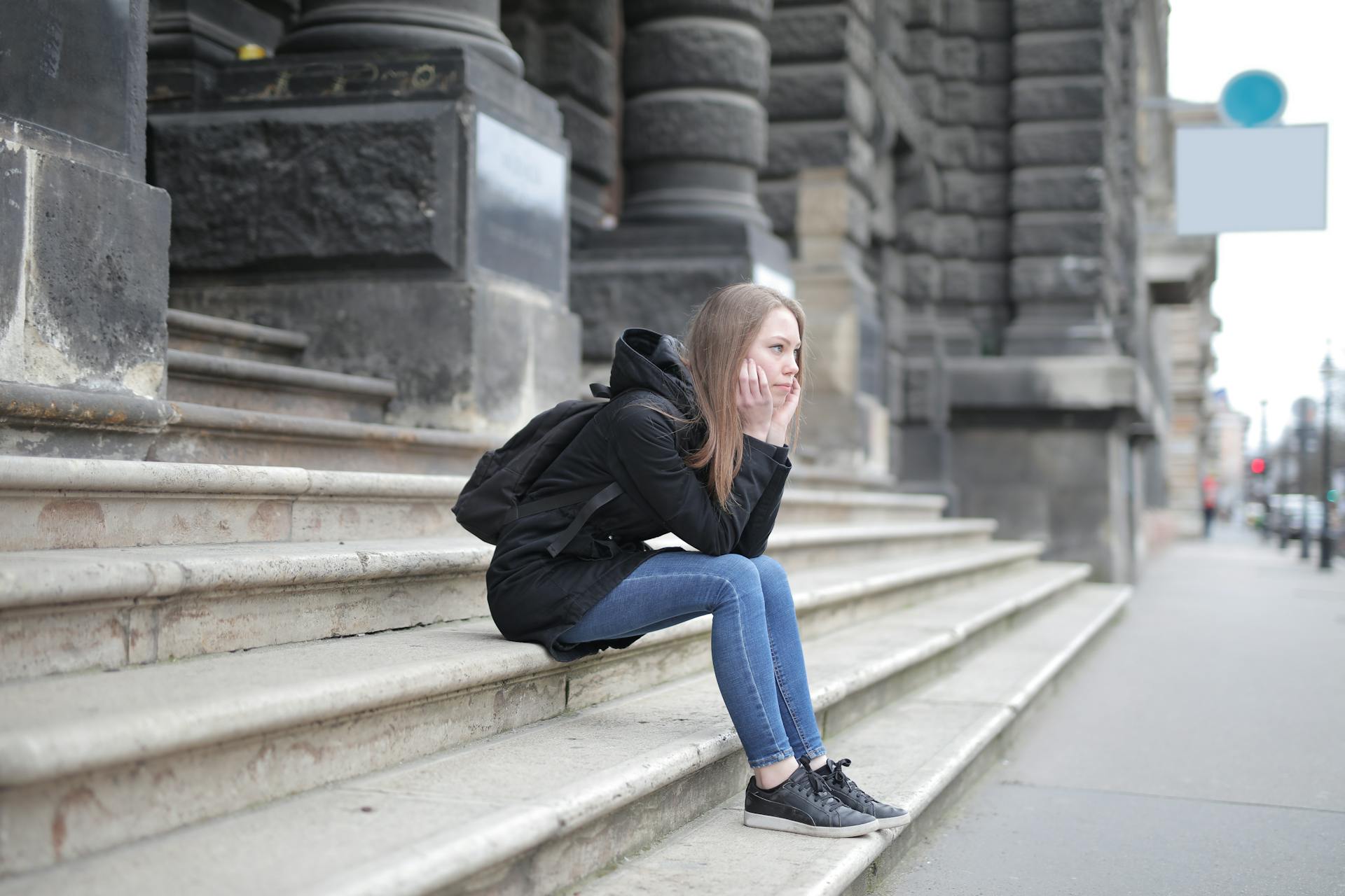 Une jeune femme pensive assise sur les escaliers d'un bâtiment ancien | Source : Pexels
